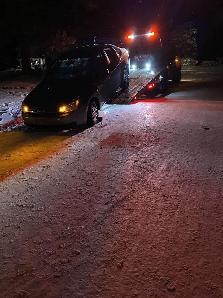 a car is driving down a snowy street at night .