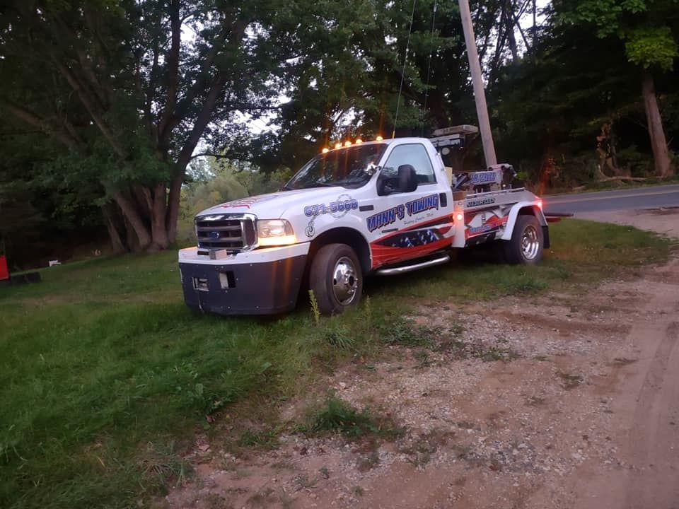 a white tow truck is parked on the side of the road .