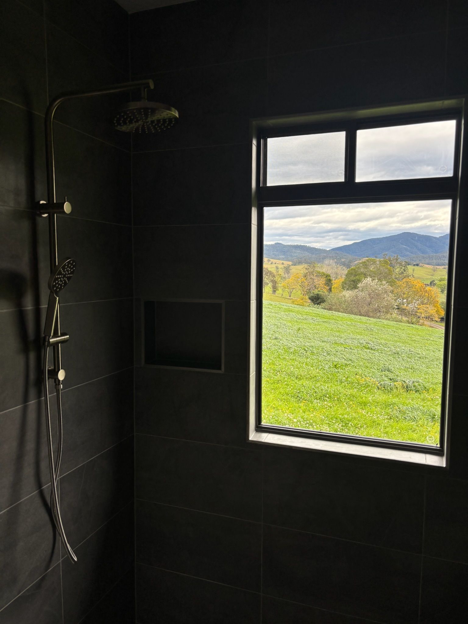 Dark Tiled Shower With a Window Offering a View — Edmonds Bathroom Renovations & Tiling In Bonny Hills, NSW