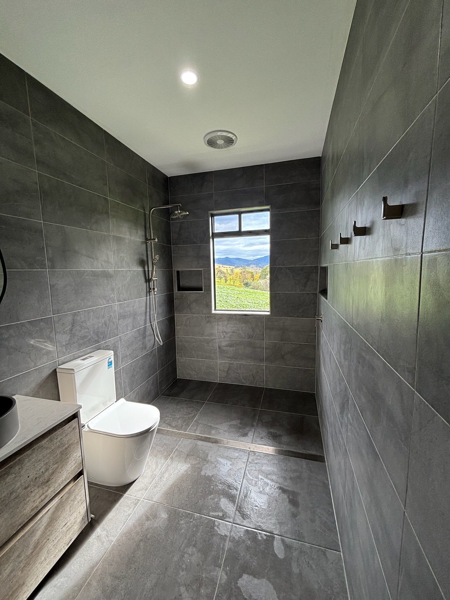 Modern Bathroom With Gray Tiled Walls, Toilet, Shower, and Window — Edmonds Bathroom Renovations & Tiling In Lake Cathie, NSW