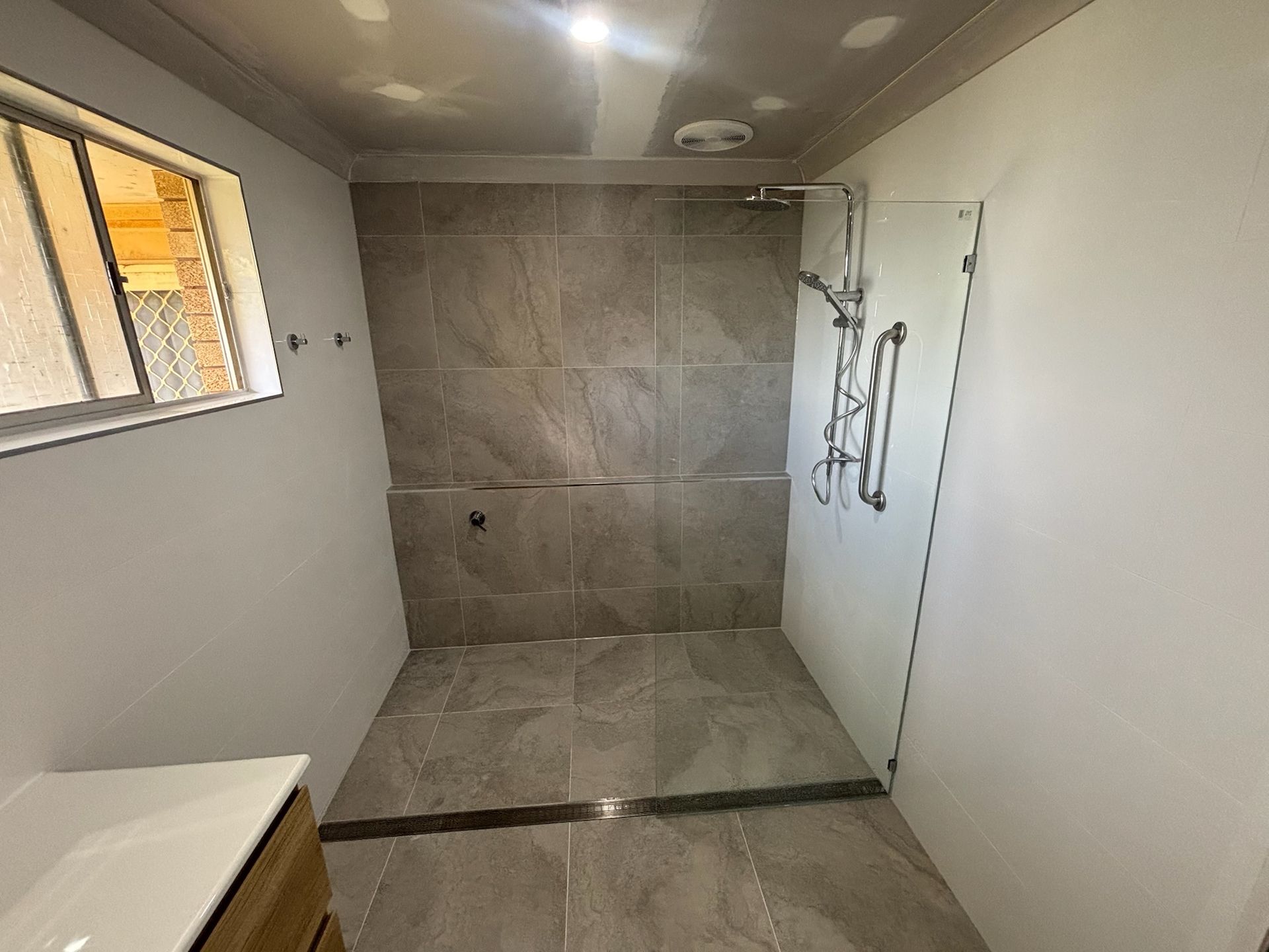 Gray-tiled Bathroom With a Glass Shower Enclosure — Edmonds Bathroom Renovations & Tiling In Port Macquarie, NSW