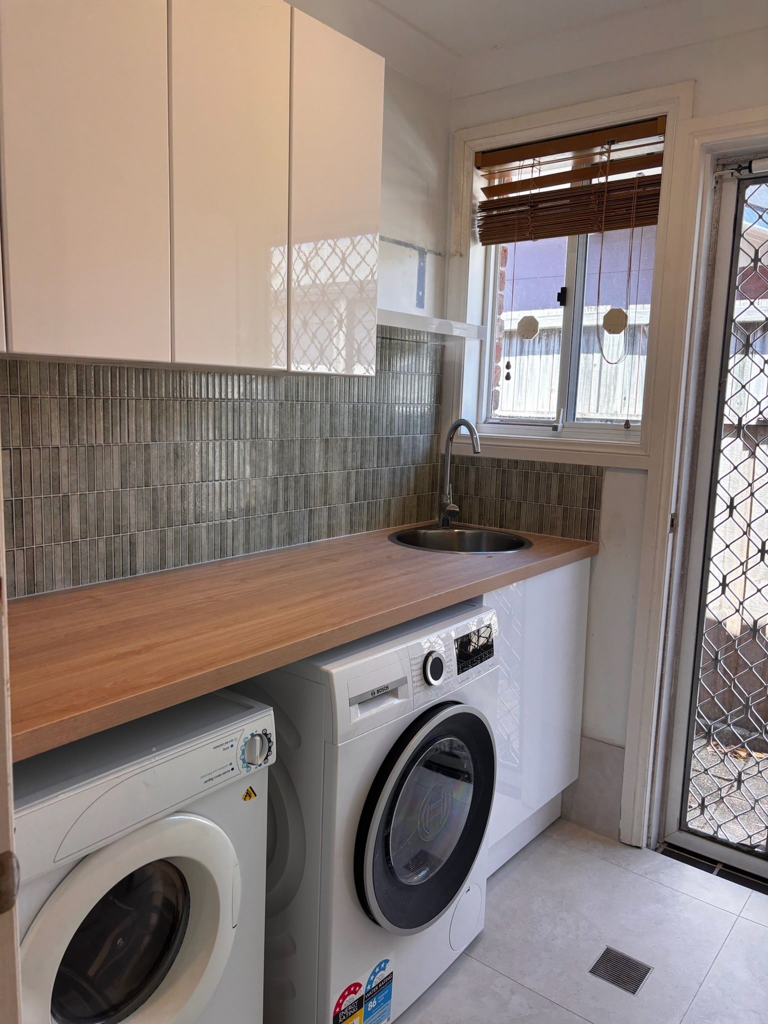 Laundry Room With Washer, Dryer, Sink, Cabinets, and a Window — Edmonds Bathroom Renovations & Tiling In Port Macquarie, NSW