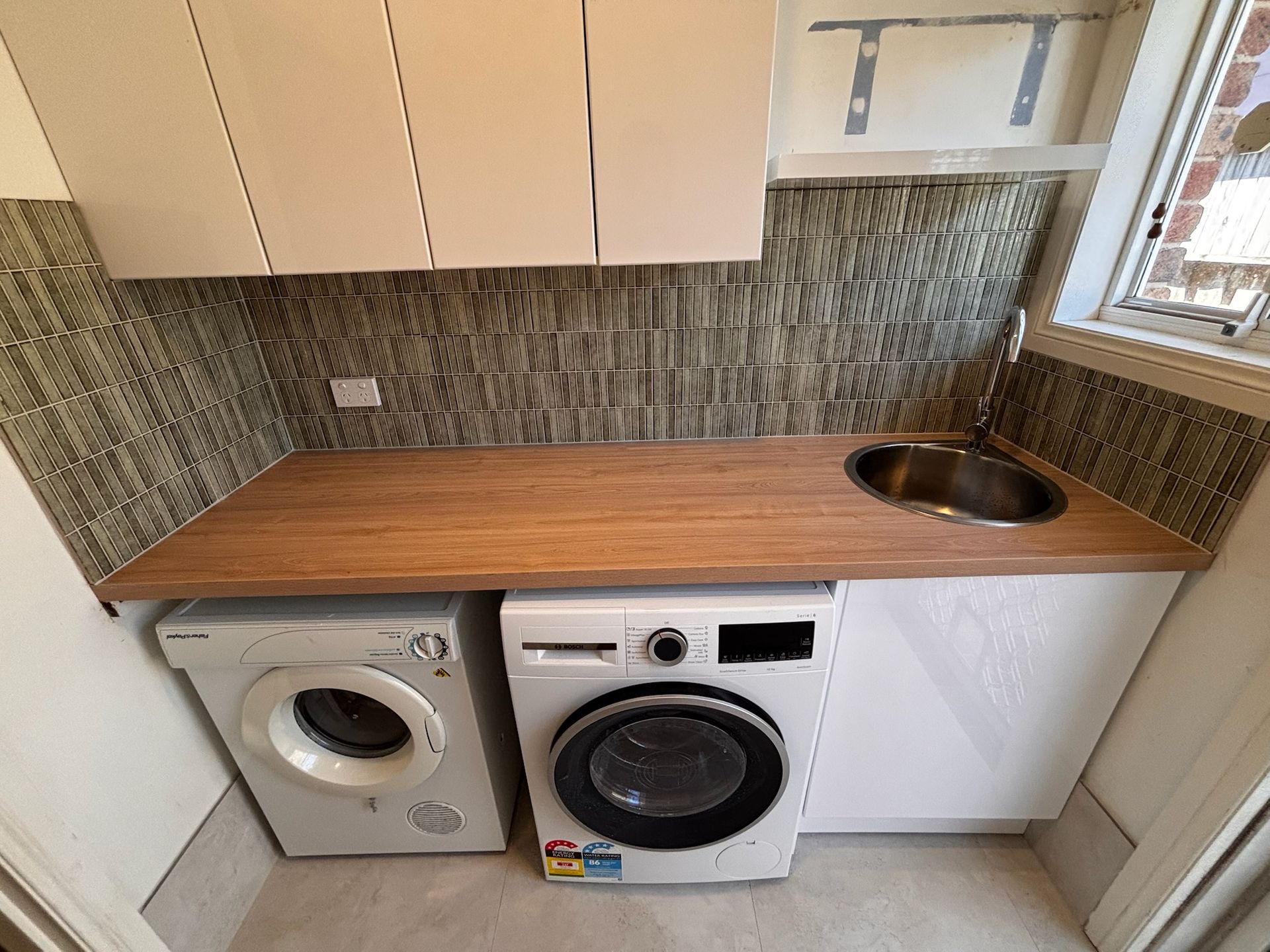 Laundry Room With a Washing Machine, Dryer, Sink, and Cabinets — Edmonds Bathroom Renovations & Tiling In Wauchope, NSW