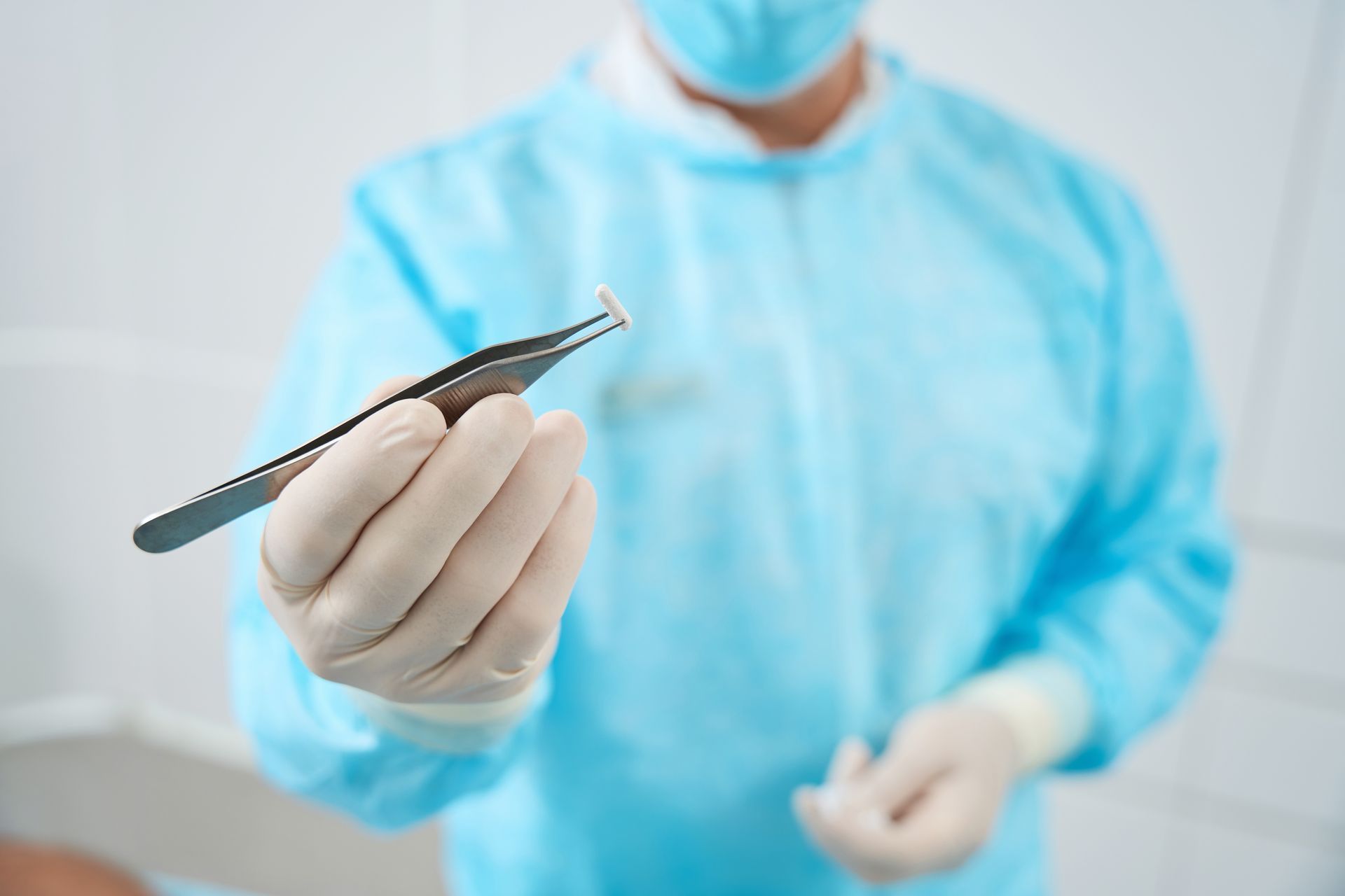 Cropped photo of doctor holds in his hand tweezers and a pellet.