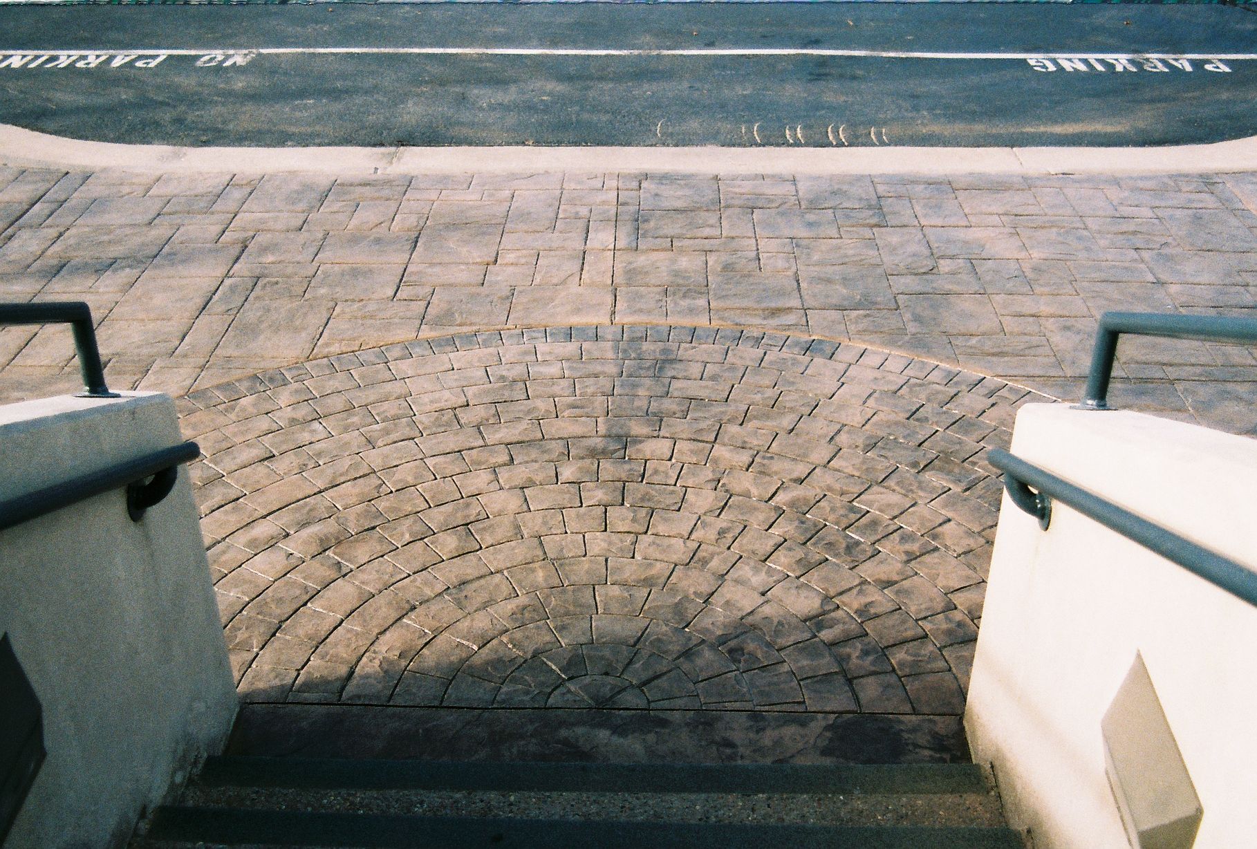 A man is pouring concrete on a sidewalk with a hose.