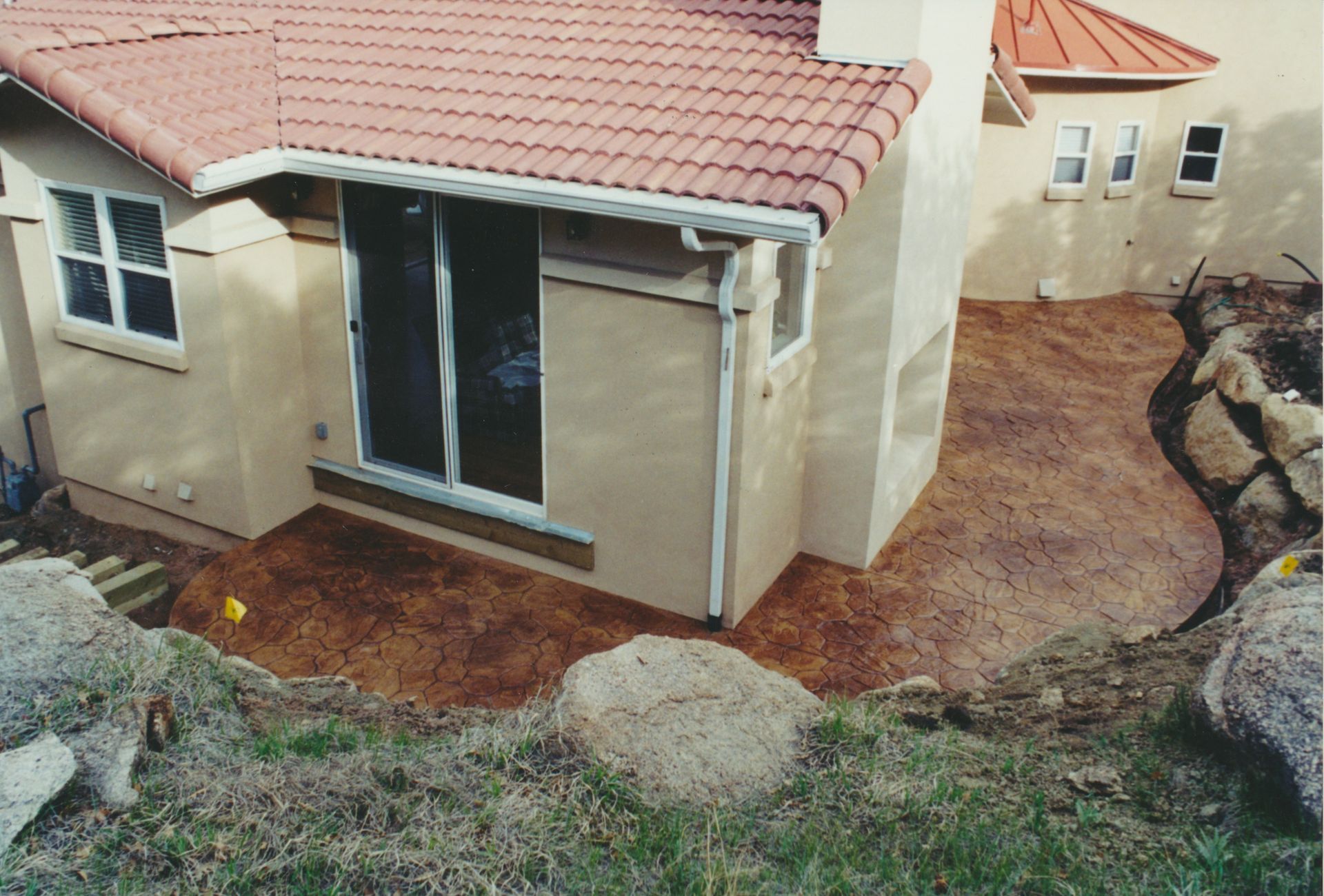 A construction worker is spreading concrete on the ground with a shovel.