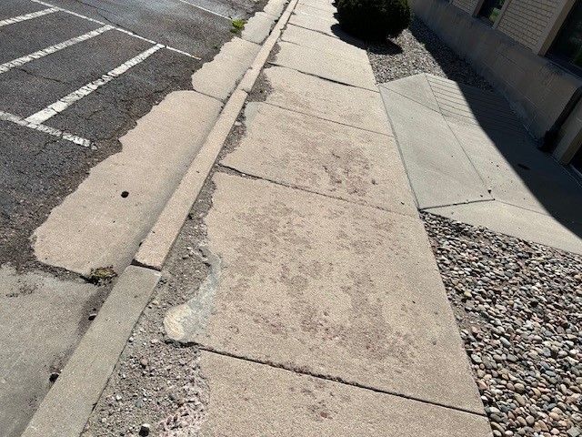 A man is spreading concrete on a sidewalk with a trowel.