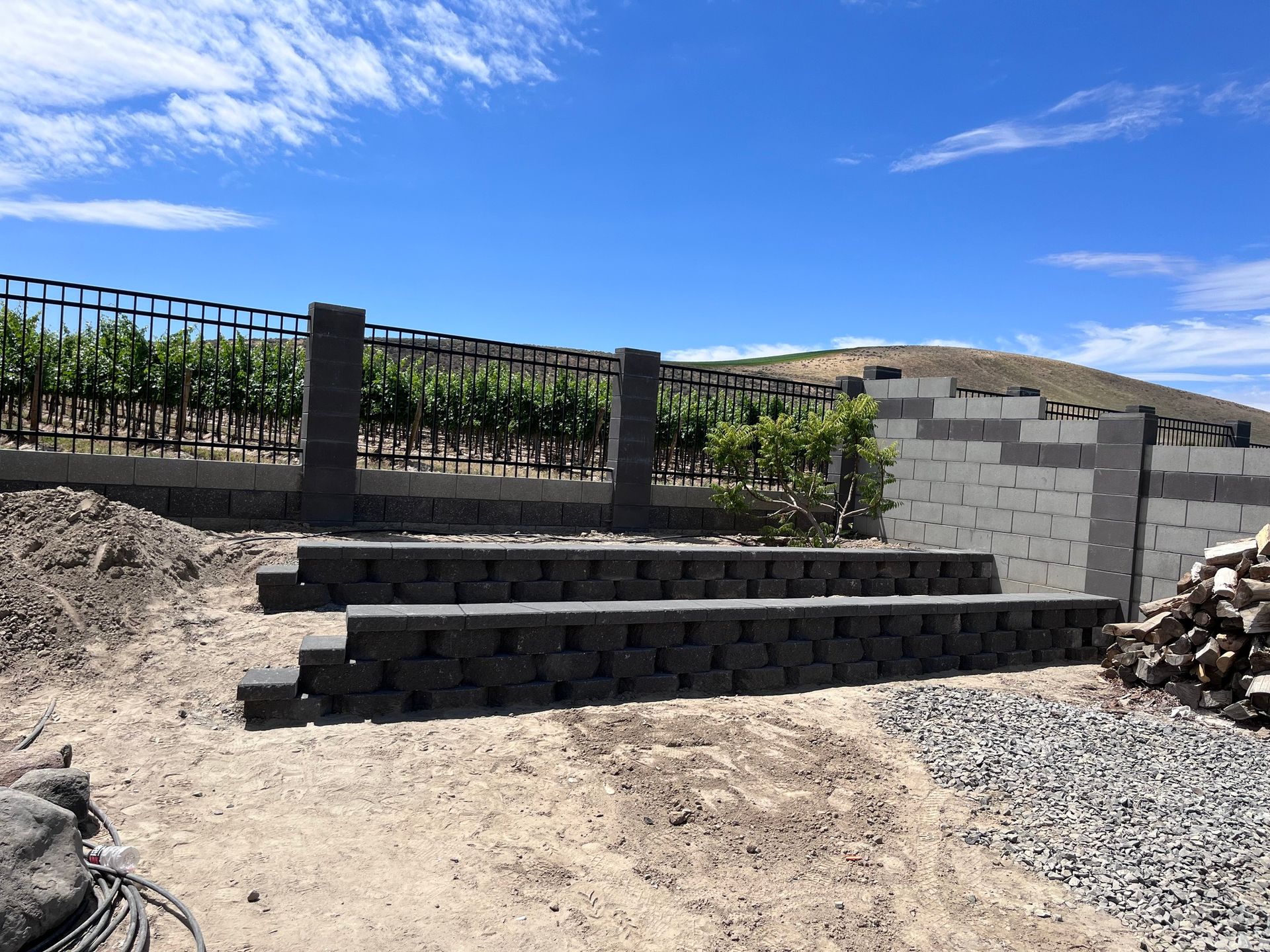 A brick wall is being built in front of a vineyard