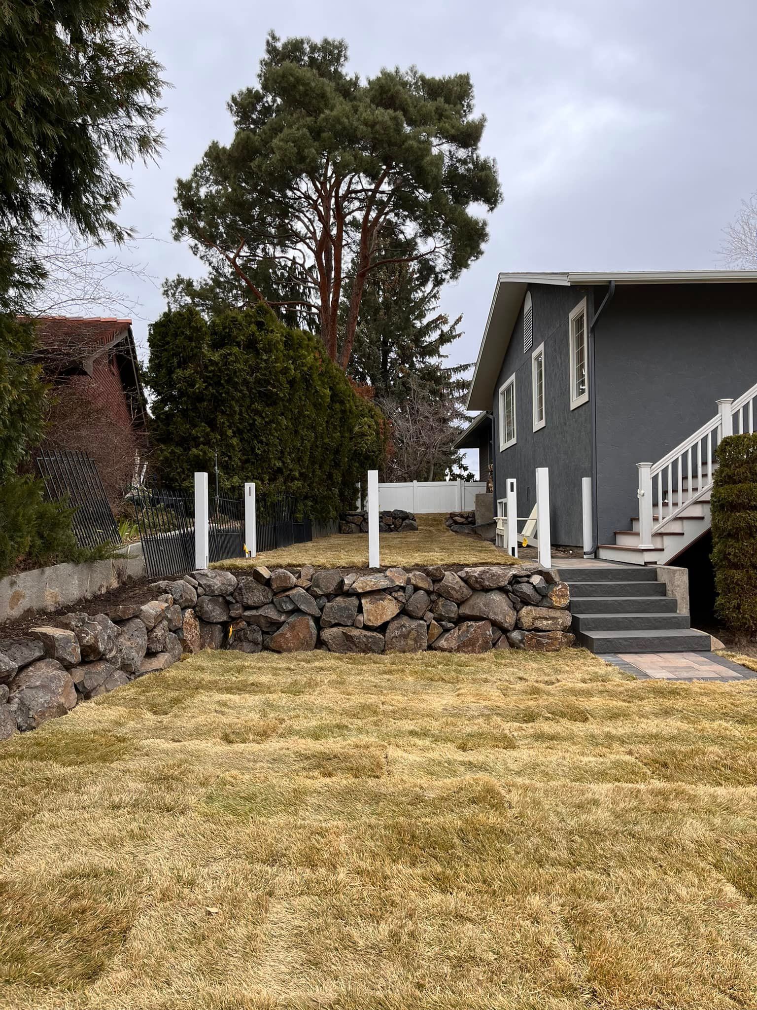 A house with stairs leading up to it and a large lawn in front of it.