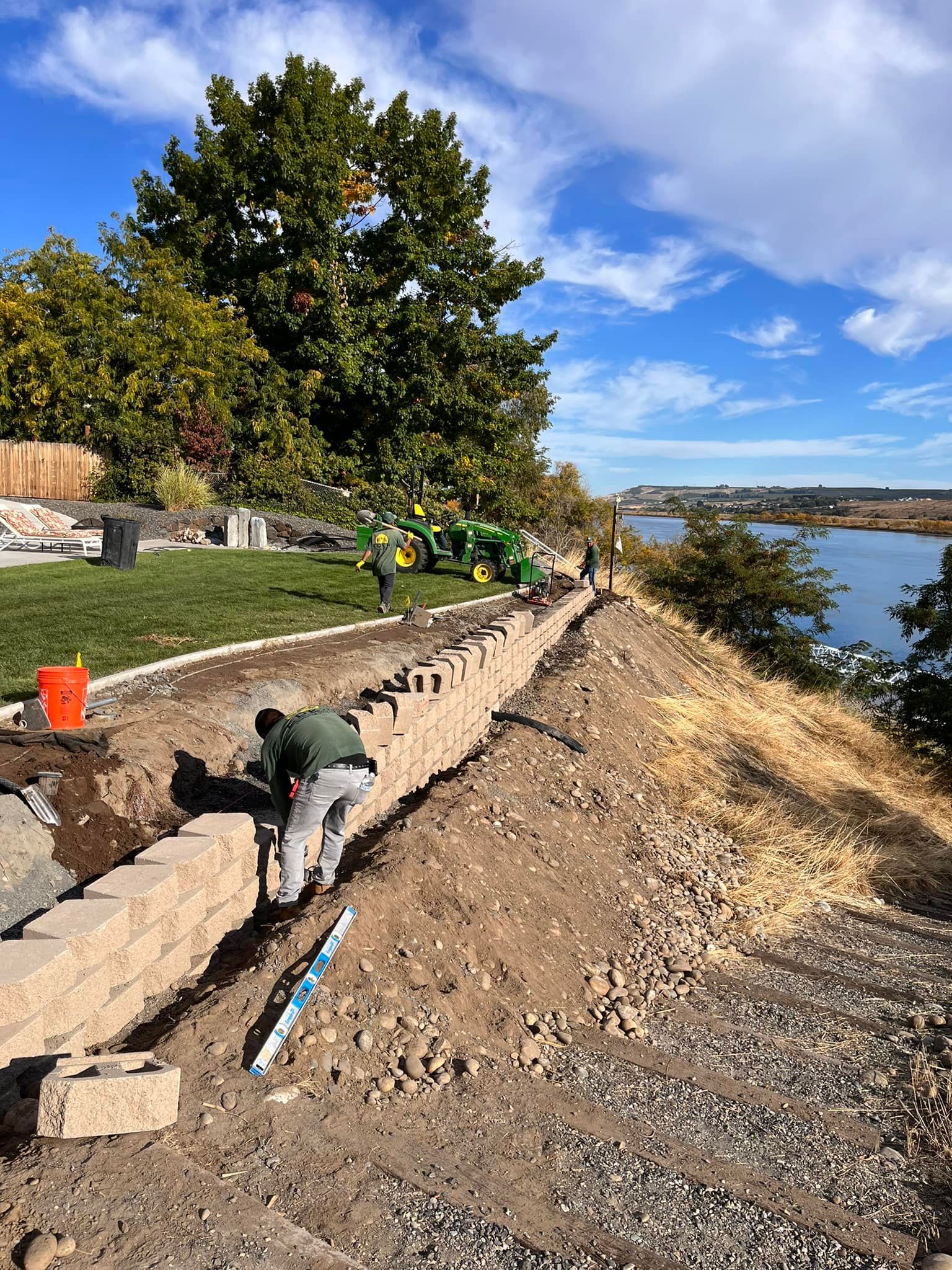 A group of people are working on a wall next to a body of water.