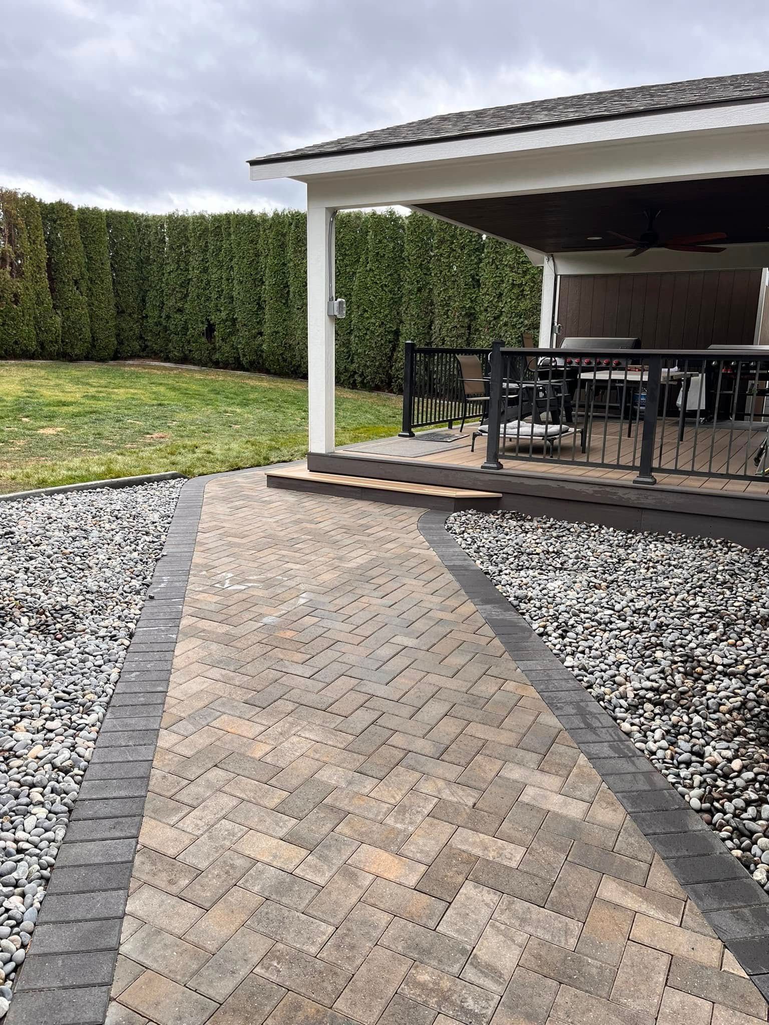A brick walkway leading to a covered patio with a table and chairs.