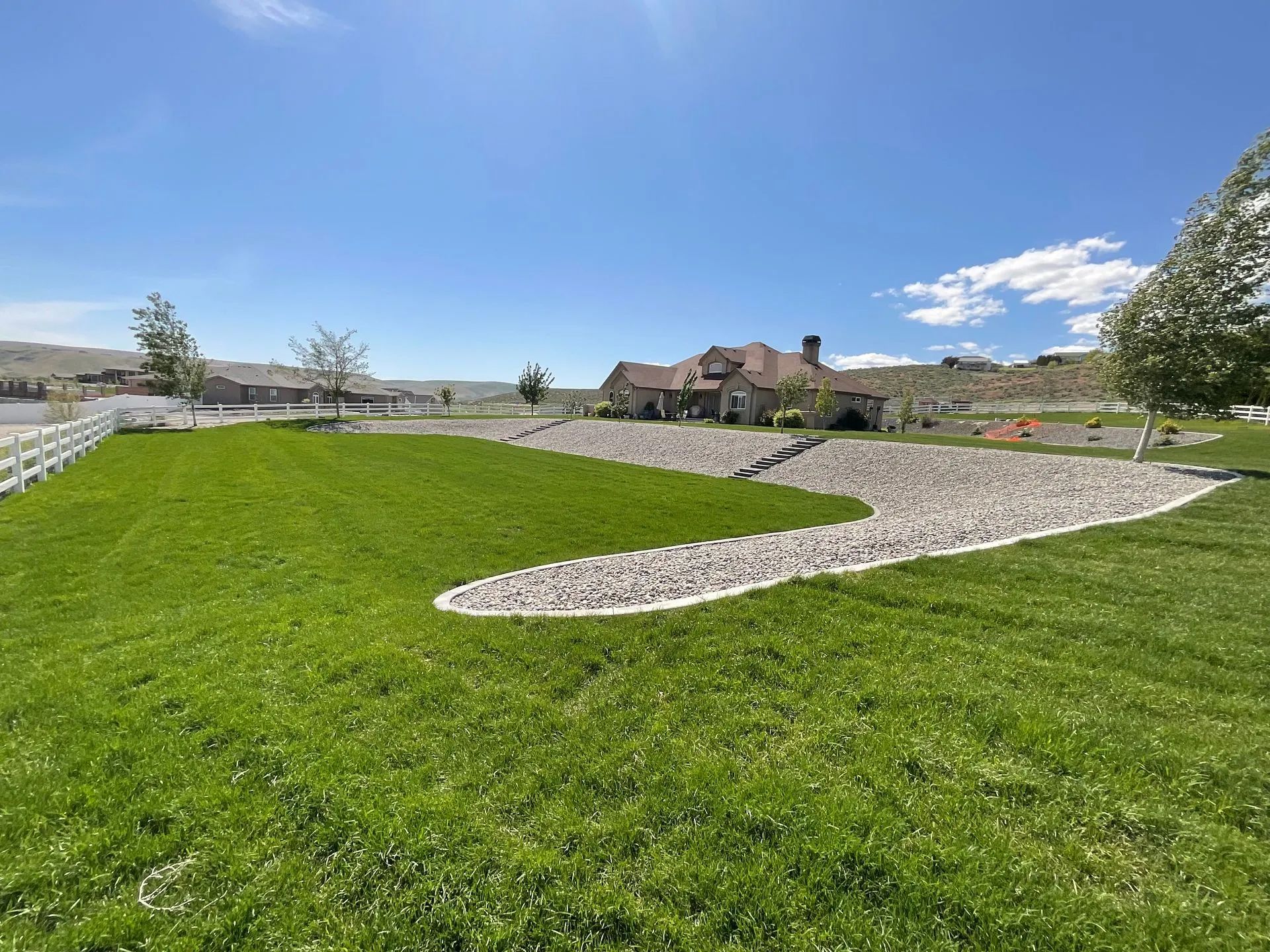 A large lush green field with a house in the background.