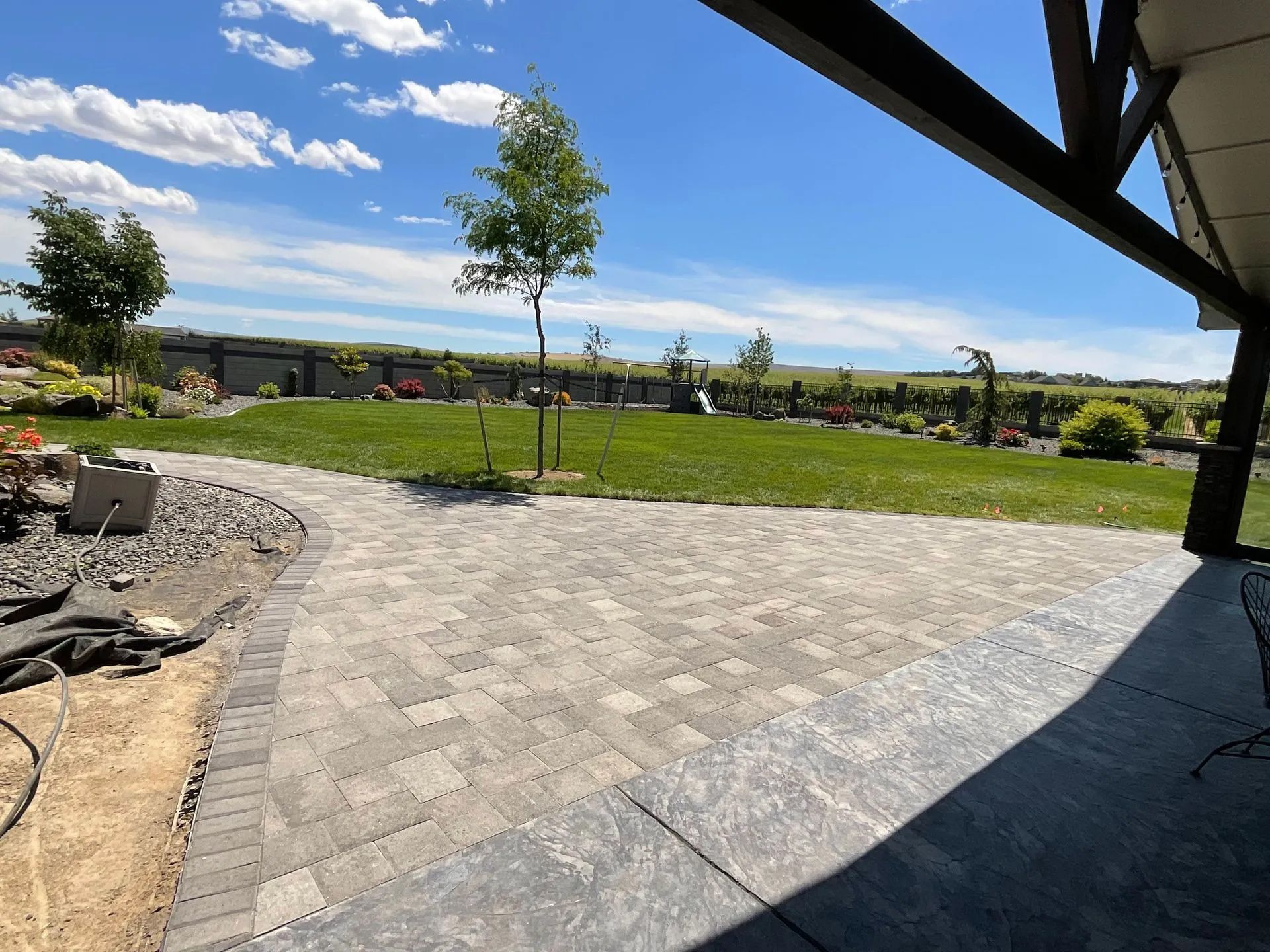 A patio with a brick walkway leading to a grassy field.