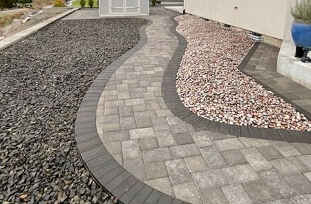 A brick walkway with gravel on the side of it