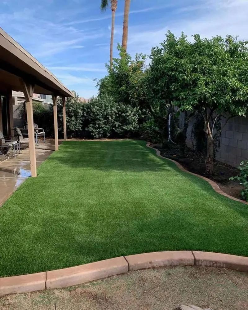 A lush green lawn in front of a house with a covered porch.