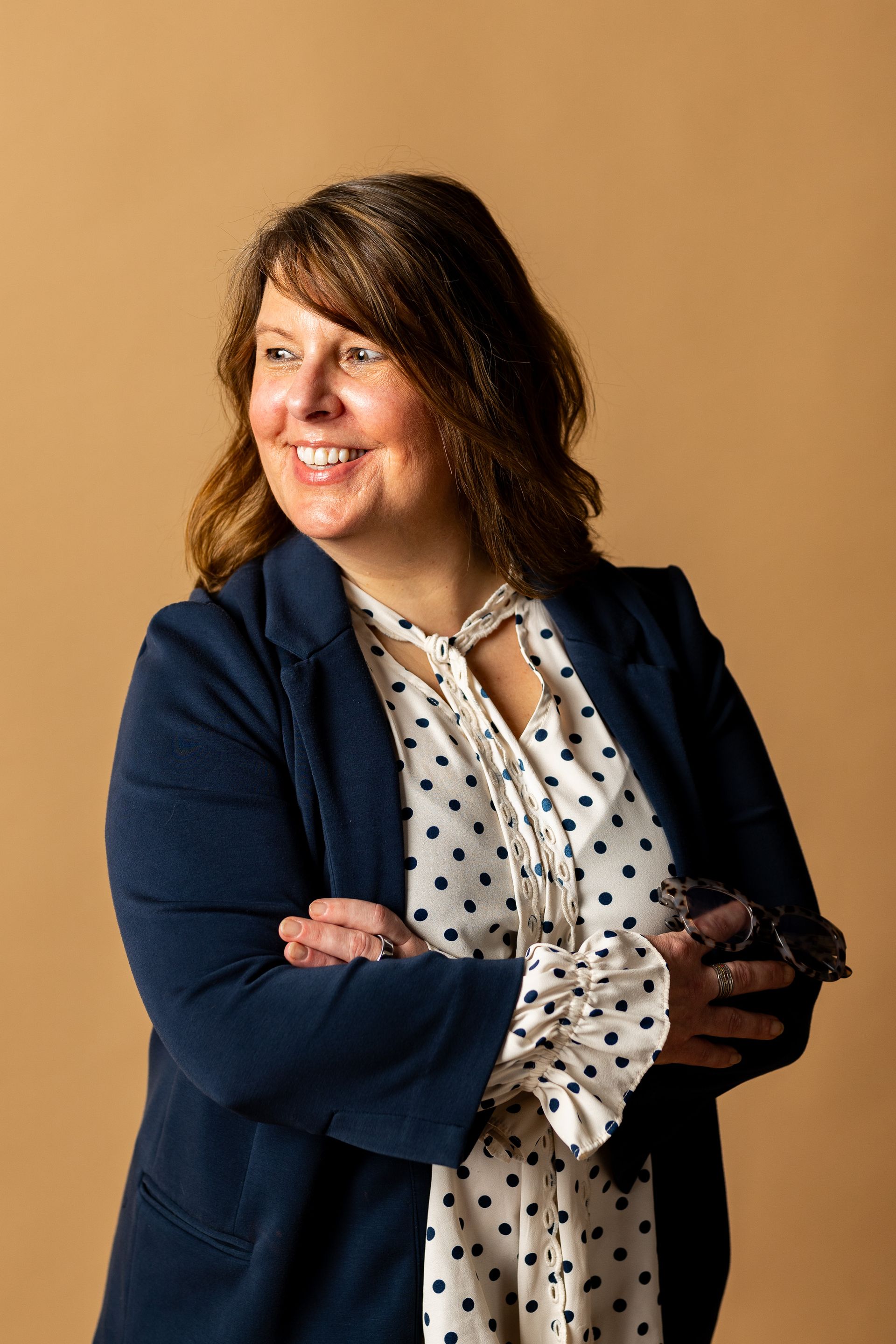 Photography MA -A woman in a blue jacket and polka dot dress is smiling.