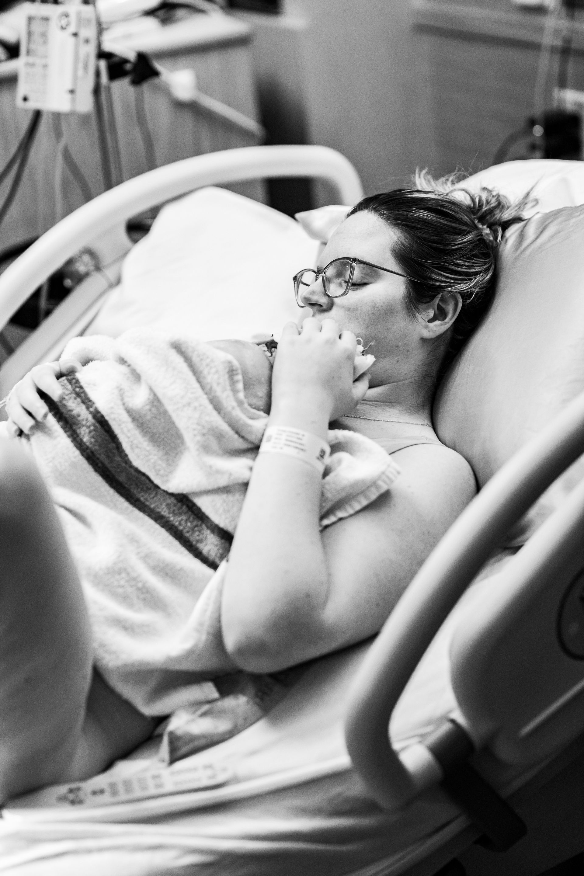 A woman is laying in a hospital bed holding a baby.