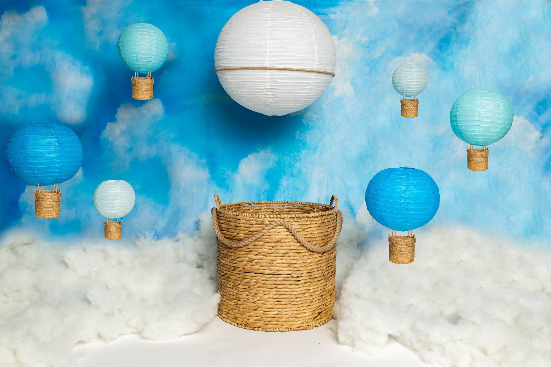 A basket is sitting in the middle of a cloudy sky surrounded by hot air balloons.