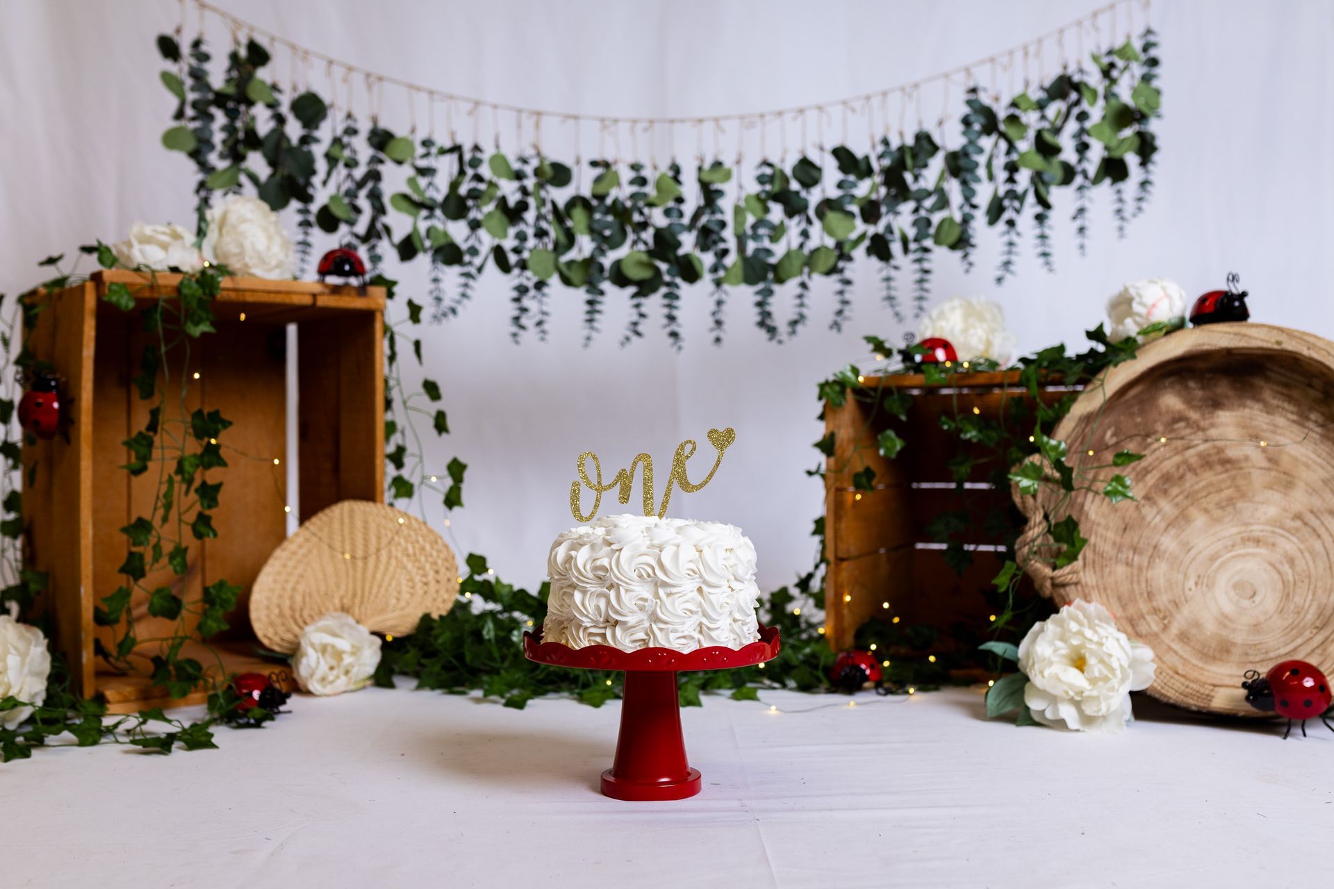 A cake is sitting on a red cake stand in front of a floral backdrop.