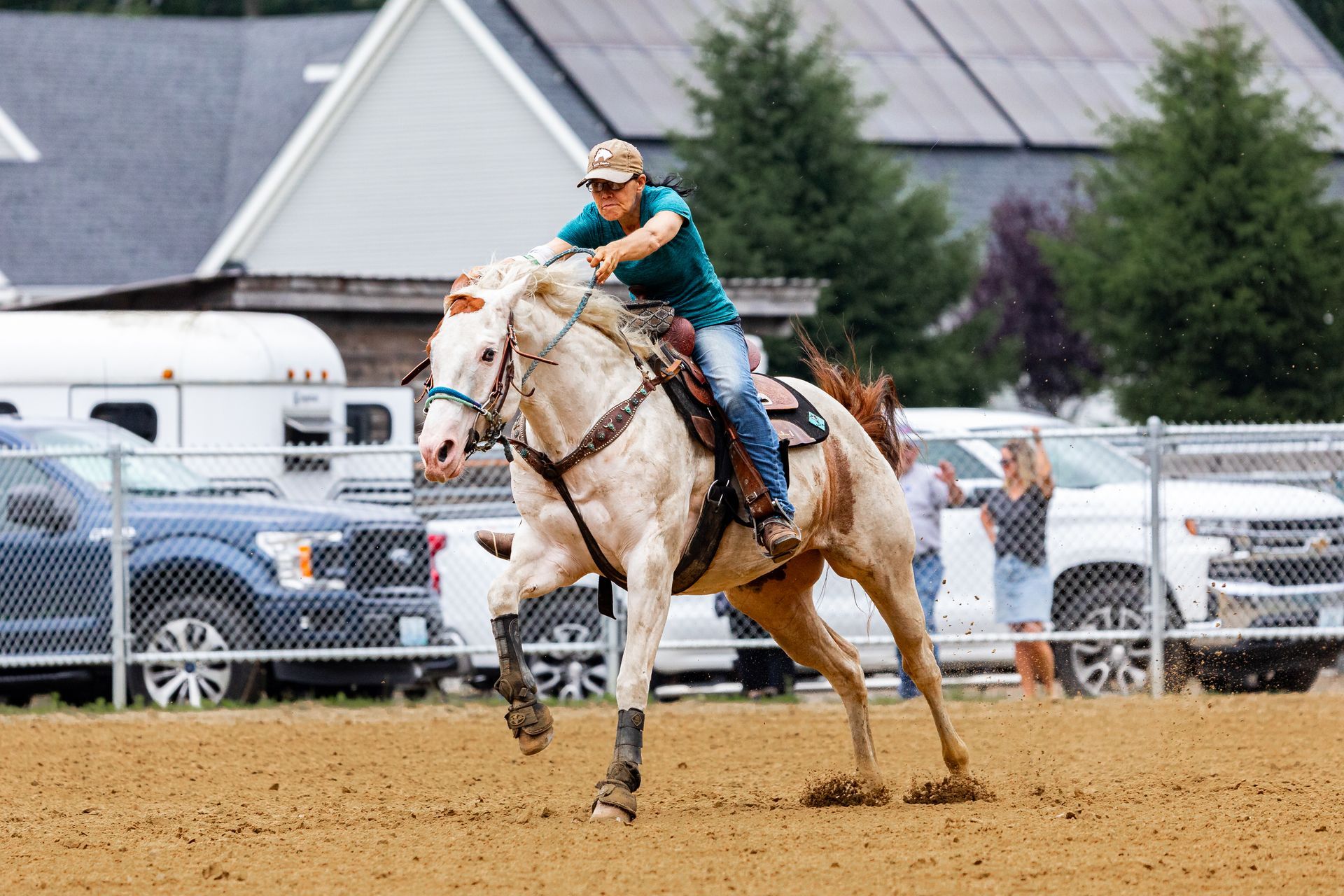 A woman is riding a white horse in a dirt field.
