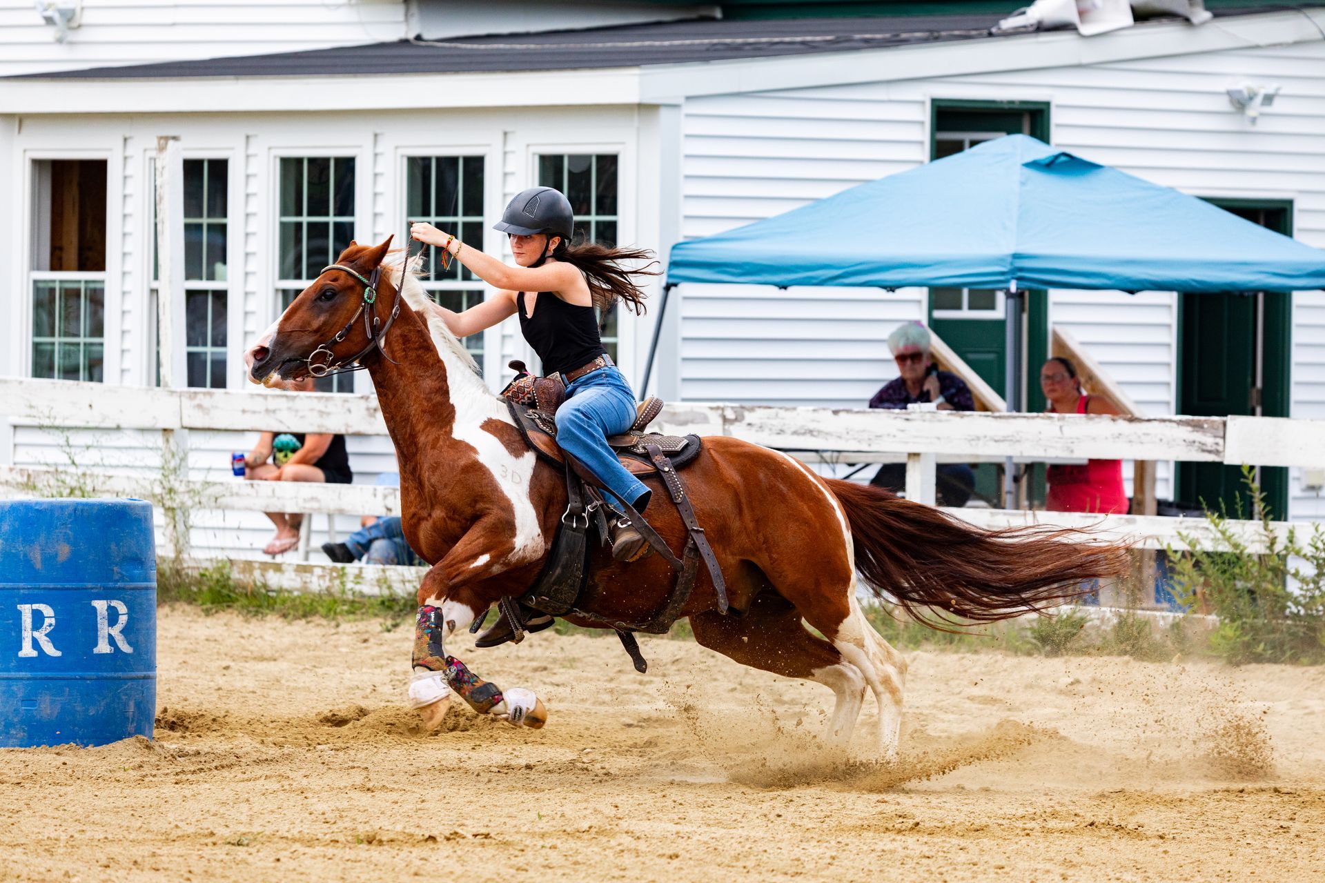 A woman is riding a brown and white horse in a barrel race.