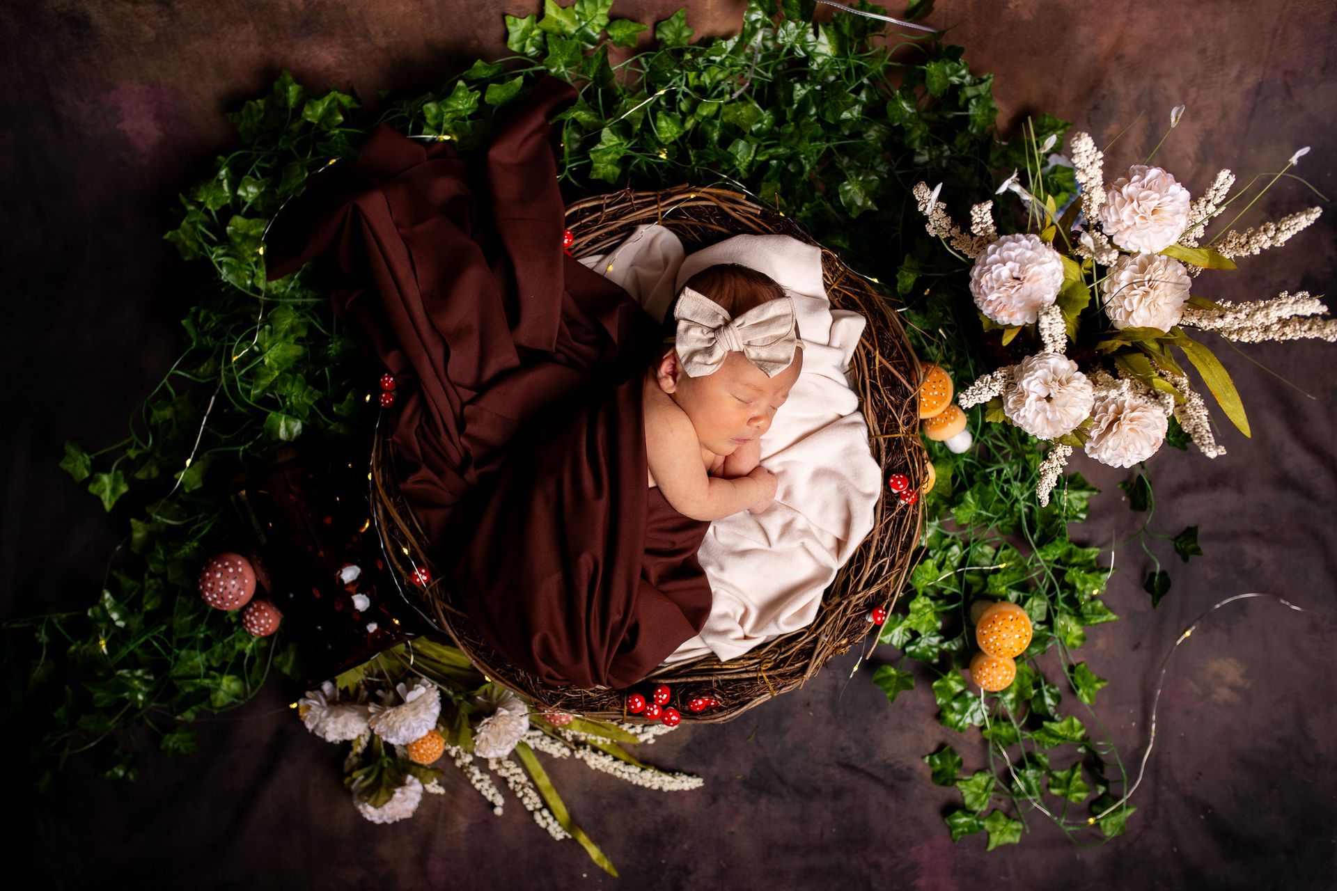 A newborn baby is wrapped in a brown swaddle on a whimsical photo set - newborn session