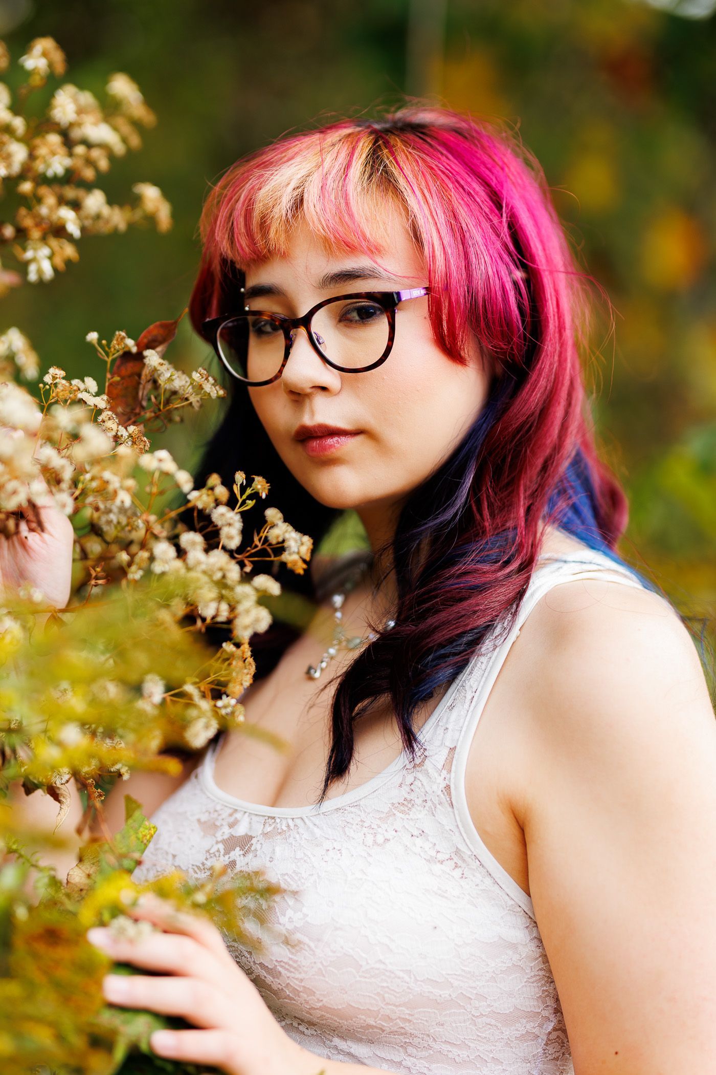 Photography MA -A woman with pink hair and glasses is holding a bouquet of flowers.