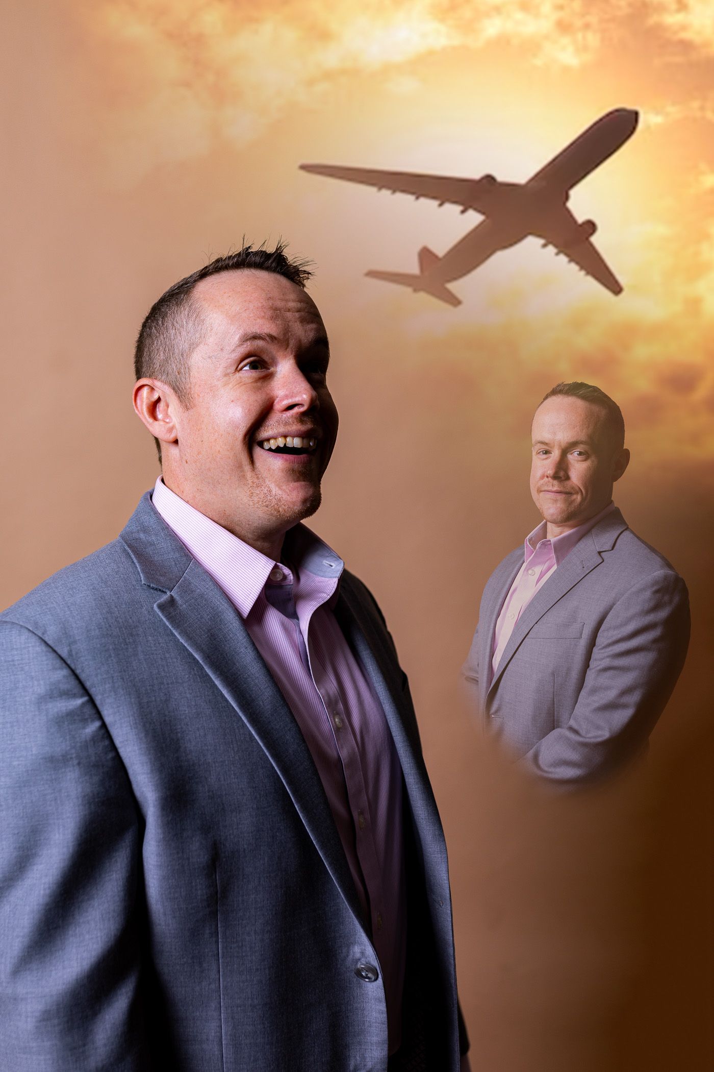 Two men in suits are standing in front of a plane flying in the sky.