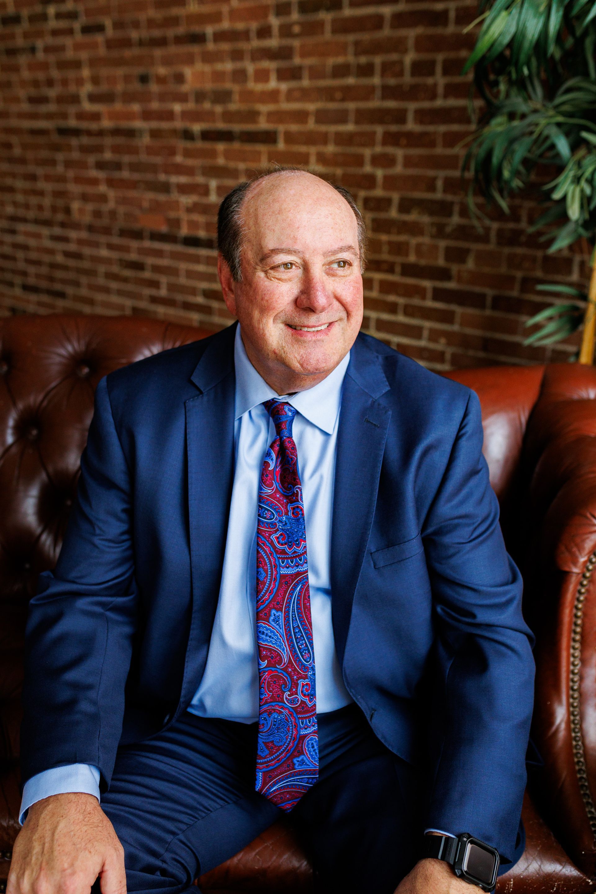 A man in a suit and tie is sitting on a couch.