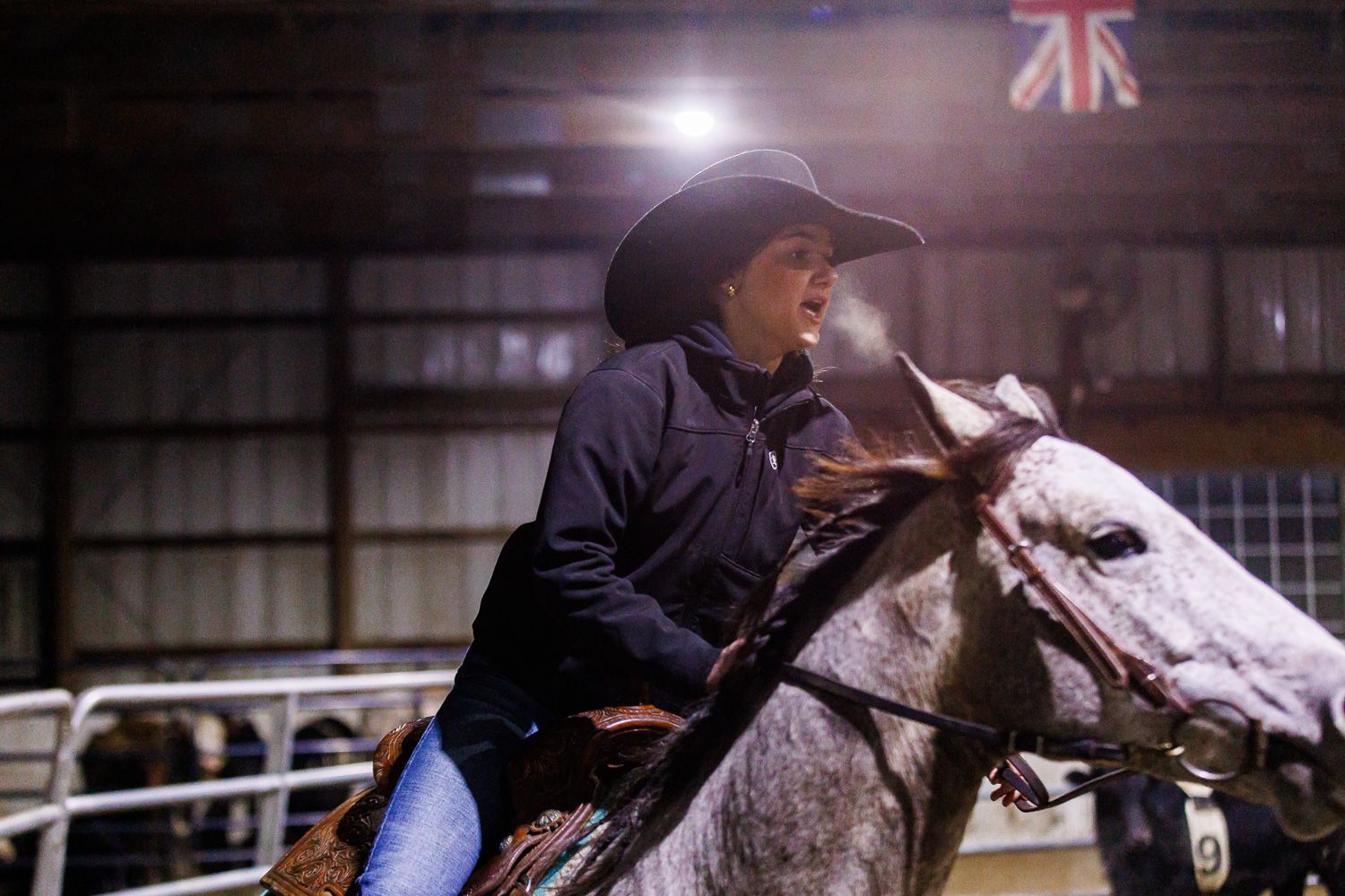 A man in a cowboy hat is riding a horse in a rodeo arena.