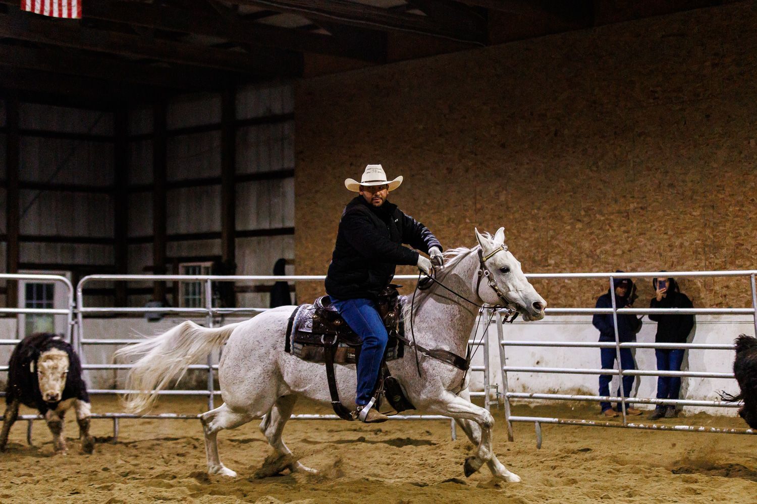 A man in a cowboy hat is riding a white horse