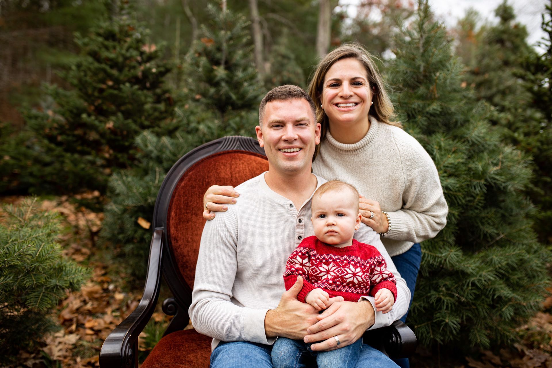 A family is posing for a picture in front of a christmas tree farm.