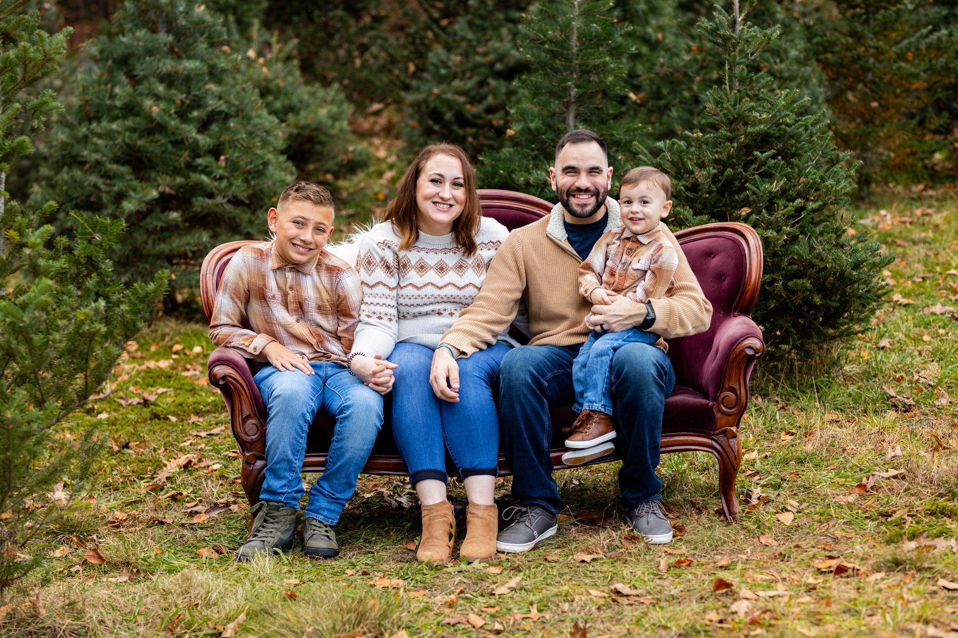 A family is sitting on a couch in the grass.