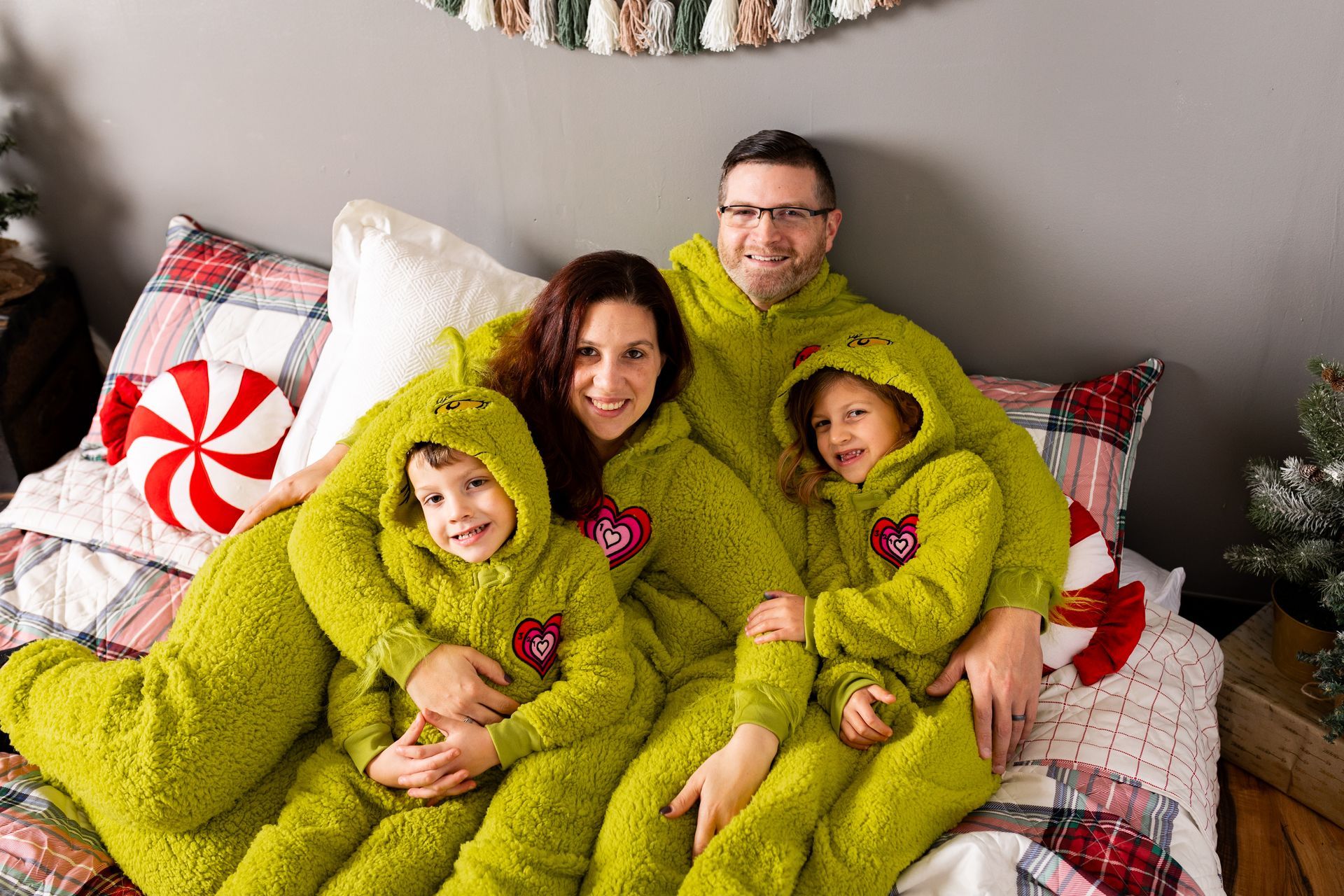 A family is laying on a bed wearing green pajamas.