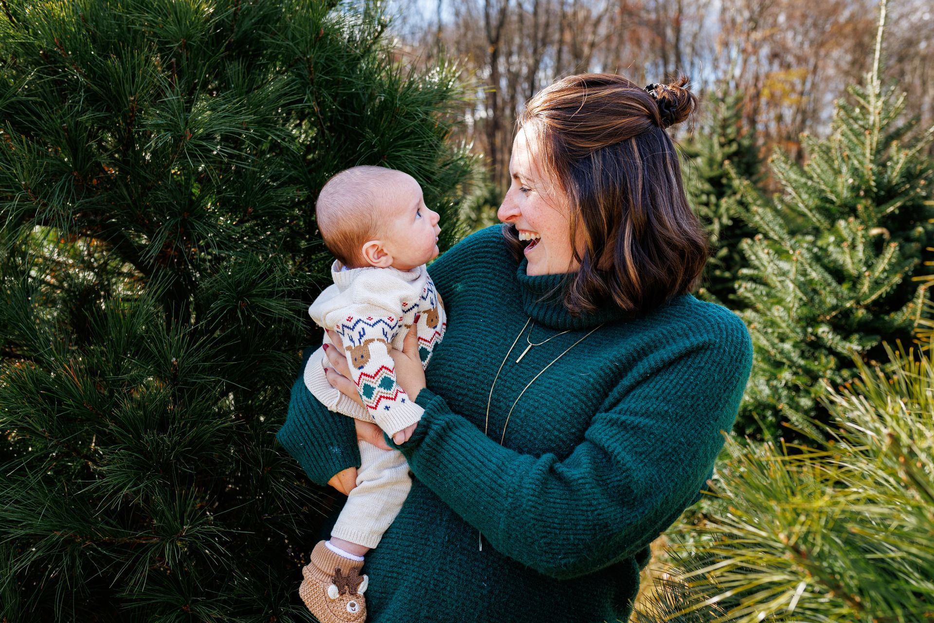 A woman is holding a baby in her arms in front of a christmas tree.