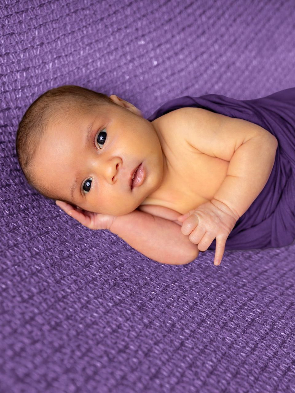 A newborn baby wrapped in a purple blanket