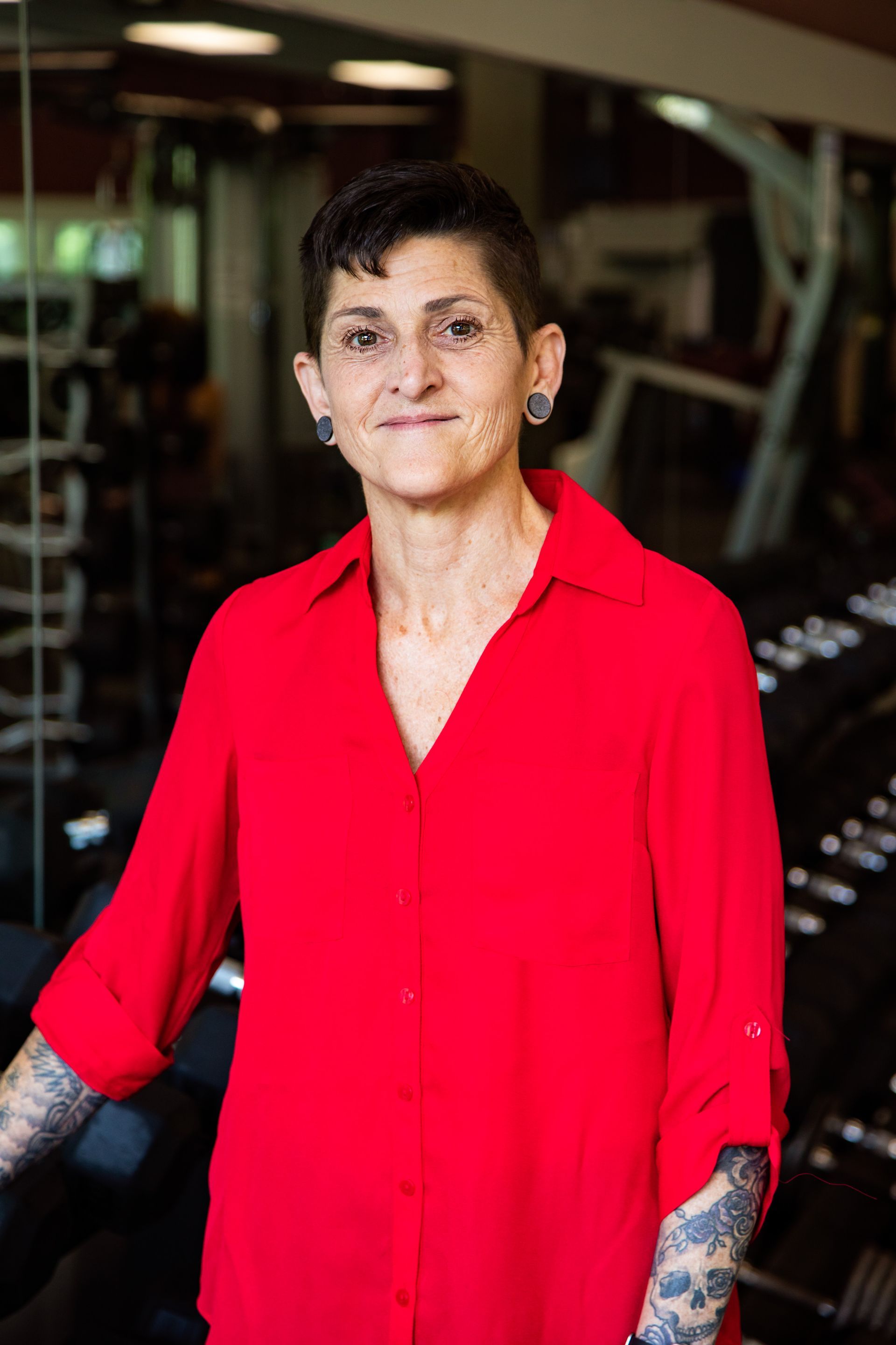 A woman in a red shirt is standing in a gym.