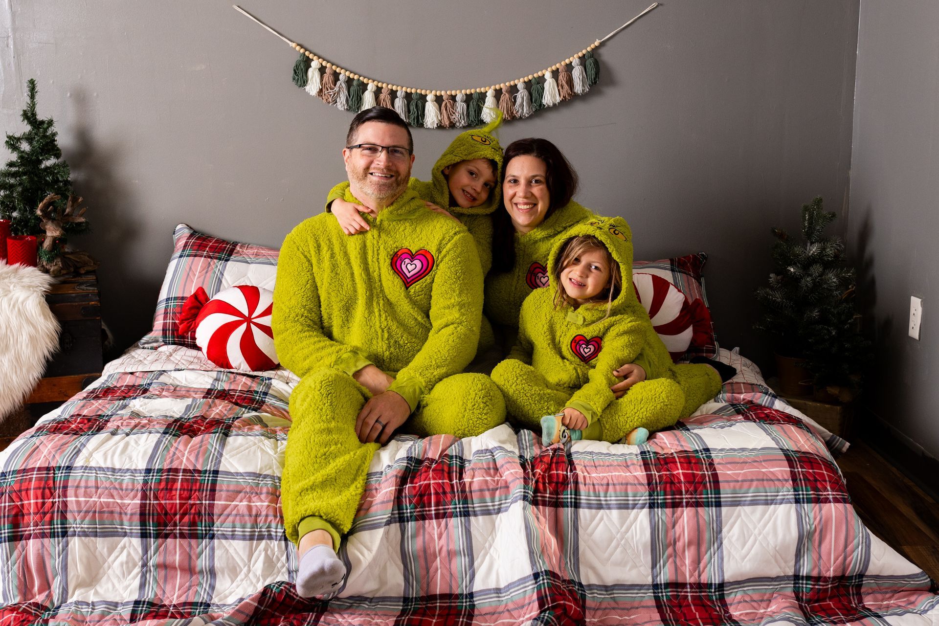 A family is sitting on a bed wearing green pajamas.