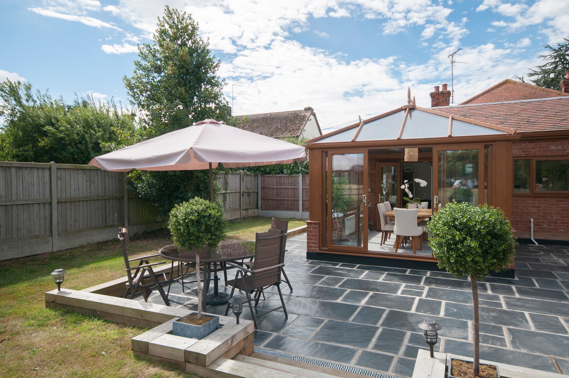 A patio with a table and chairs and an umbrella in front of a house.