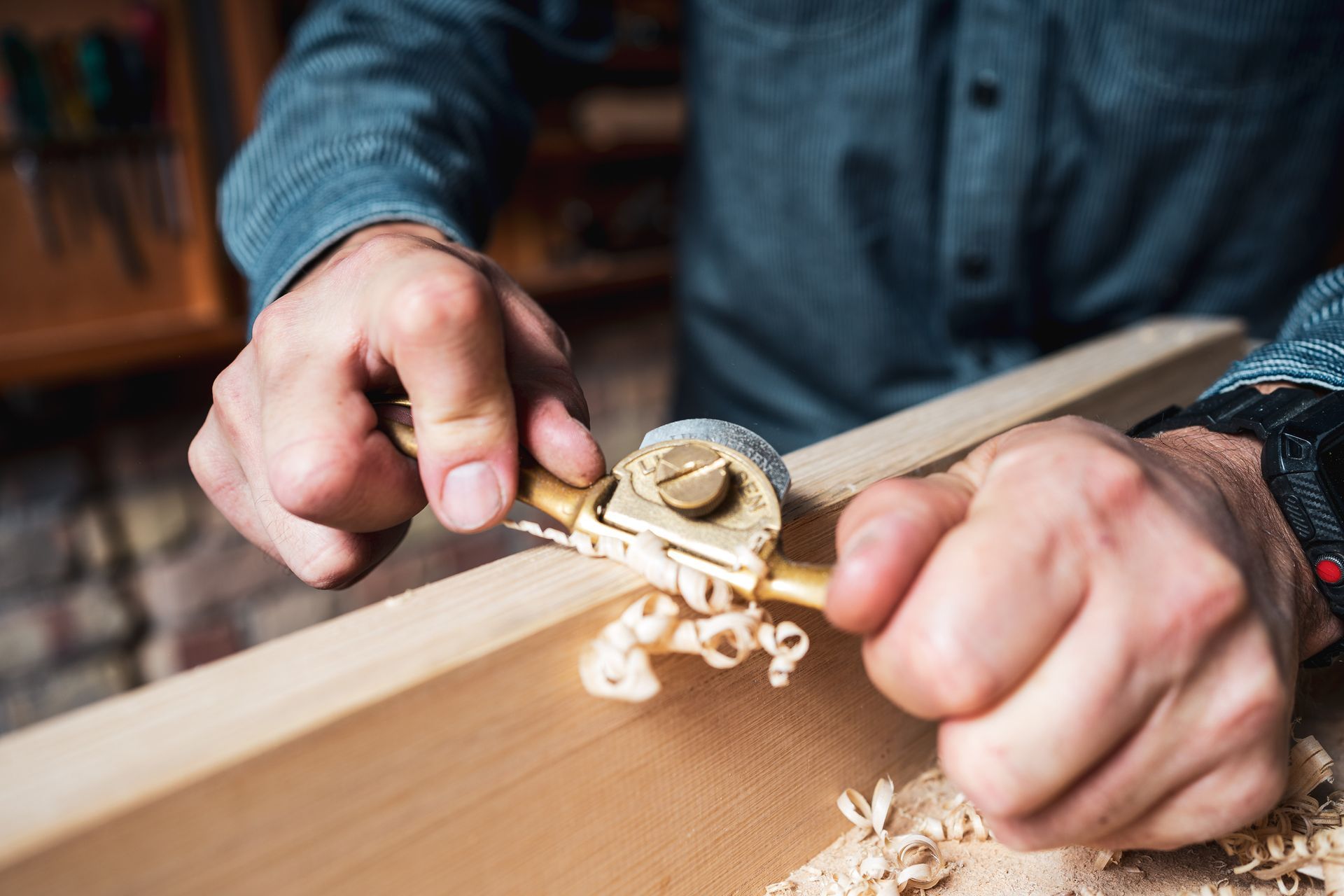 A man is using a plane to carve a piece of wood.