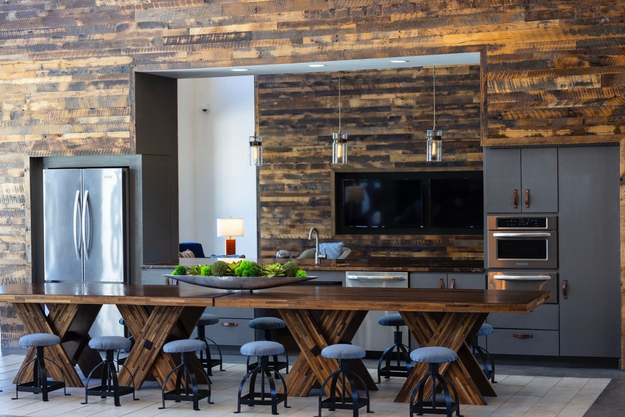 Modern kitchen with wood-paneled wall, large island, and stainless steel appliances.
