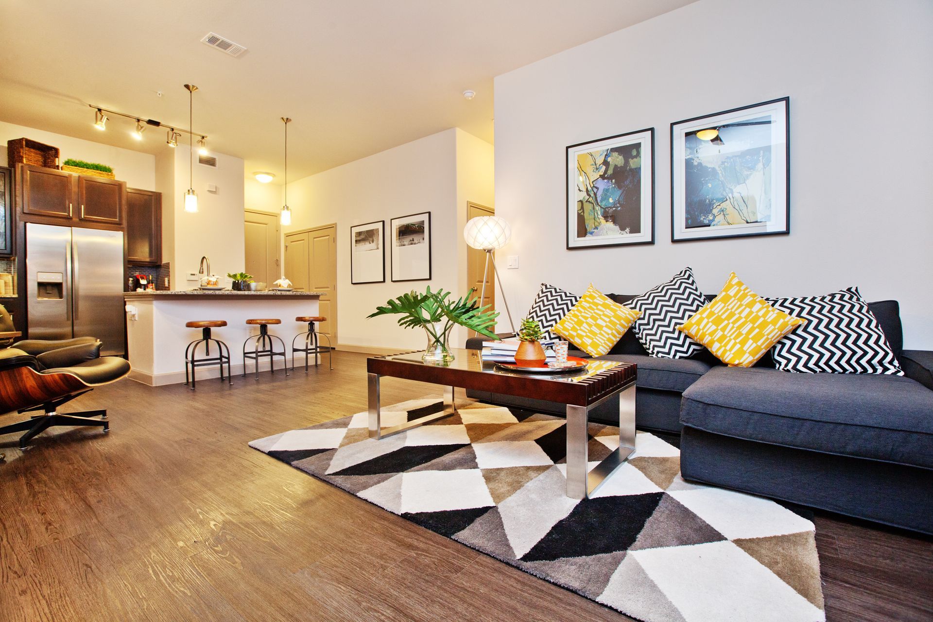 Open-concept living area with kitchen island, bar stools, and a gray sofa.
