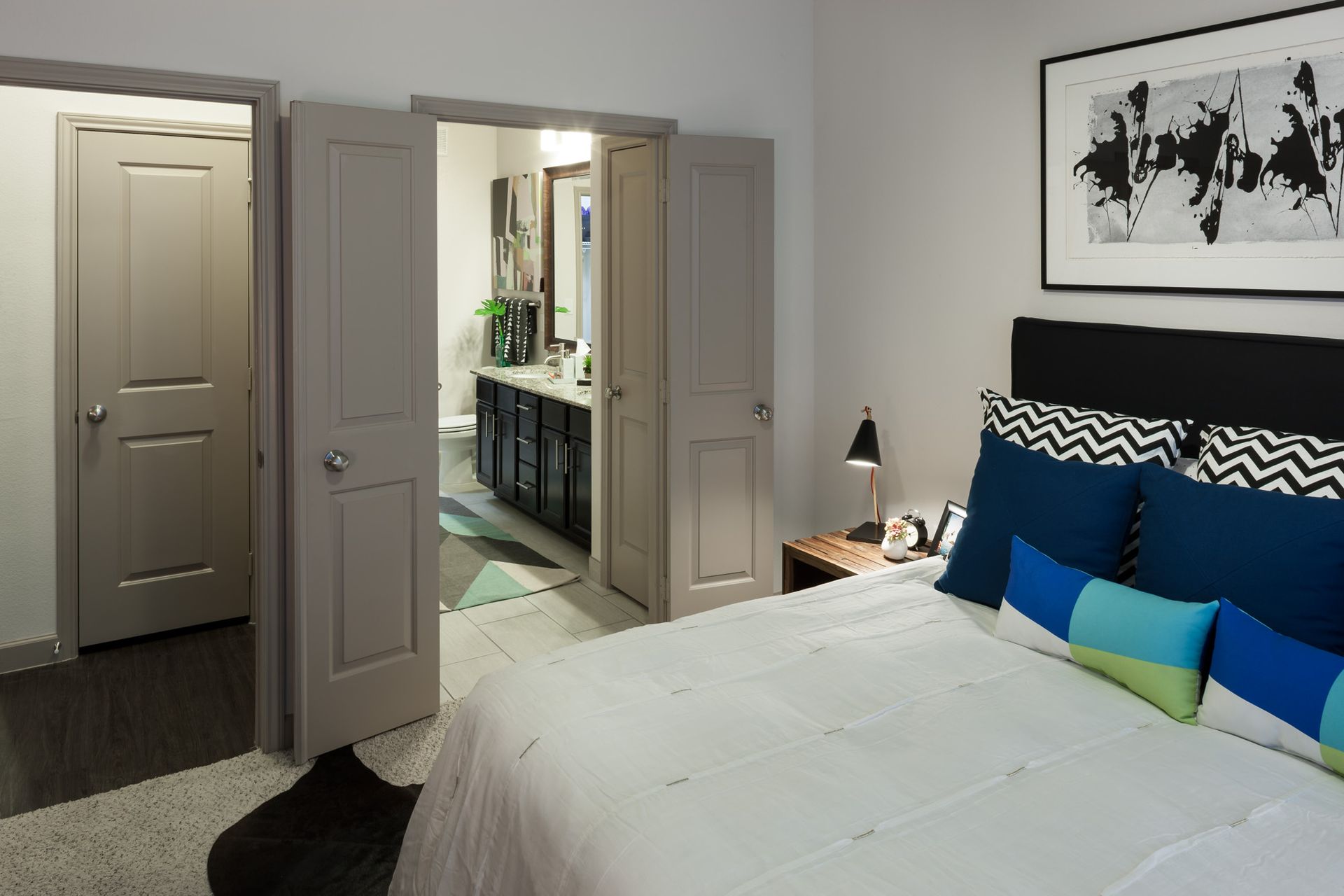 Bedroom with a large bed, nightstand, and open doorway to the bathroom.