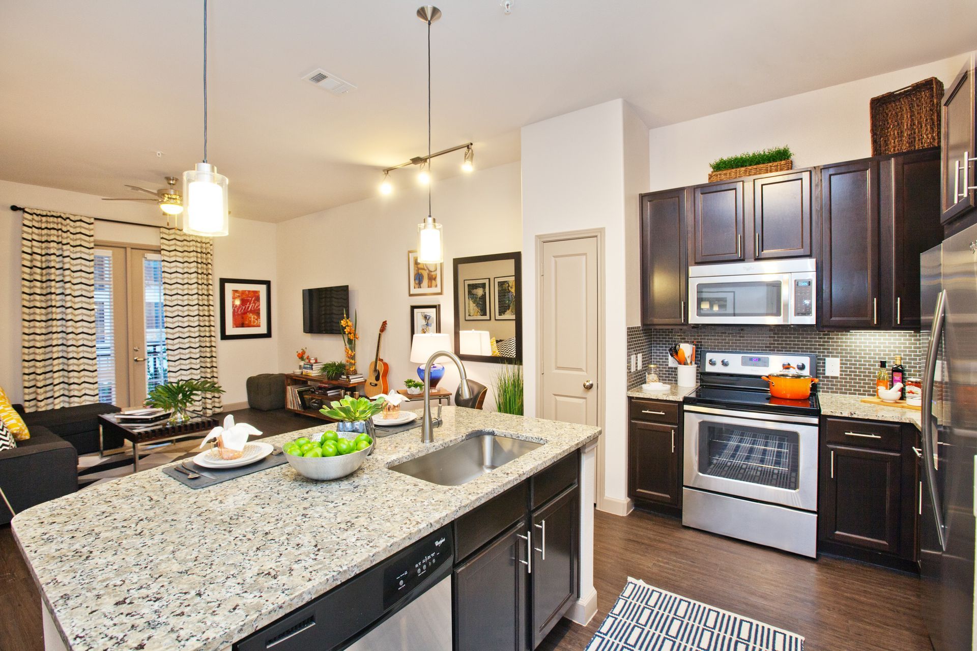 Open-concept kitchen with granite island, dark wood cabinets, and stainless-steel appliances.