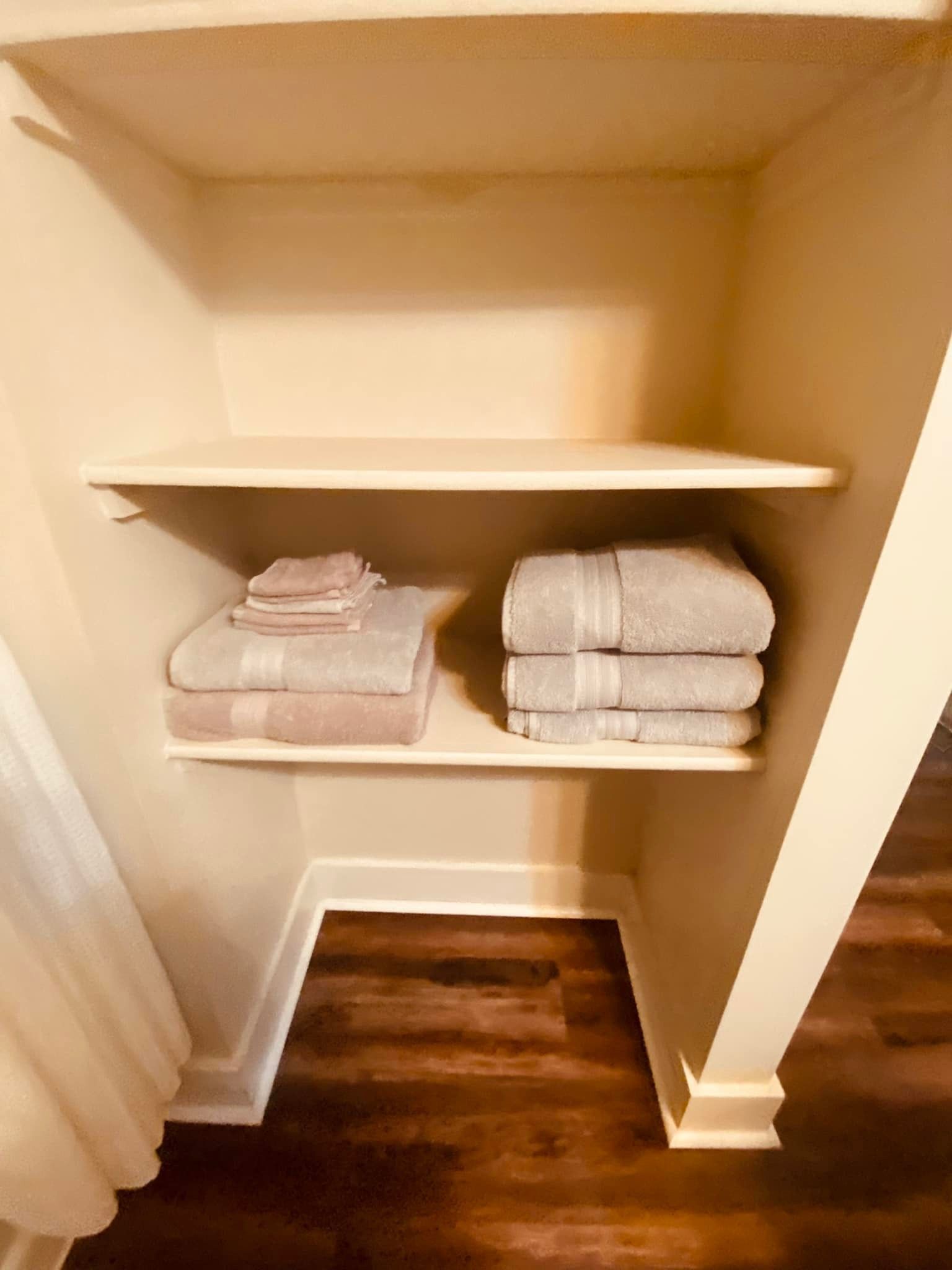 A closet with two shelves filled with stacks of towels.