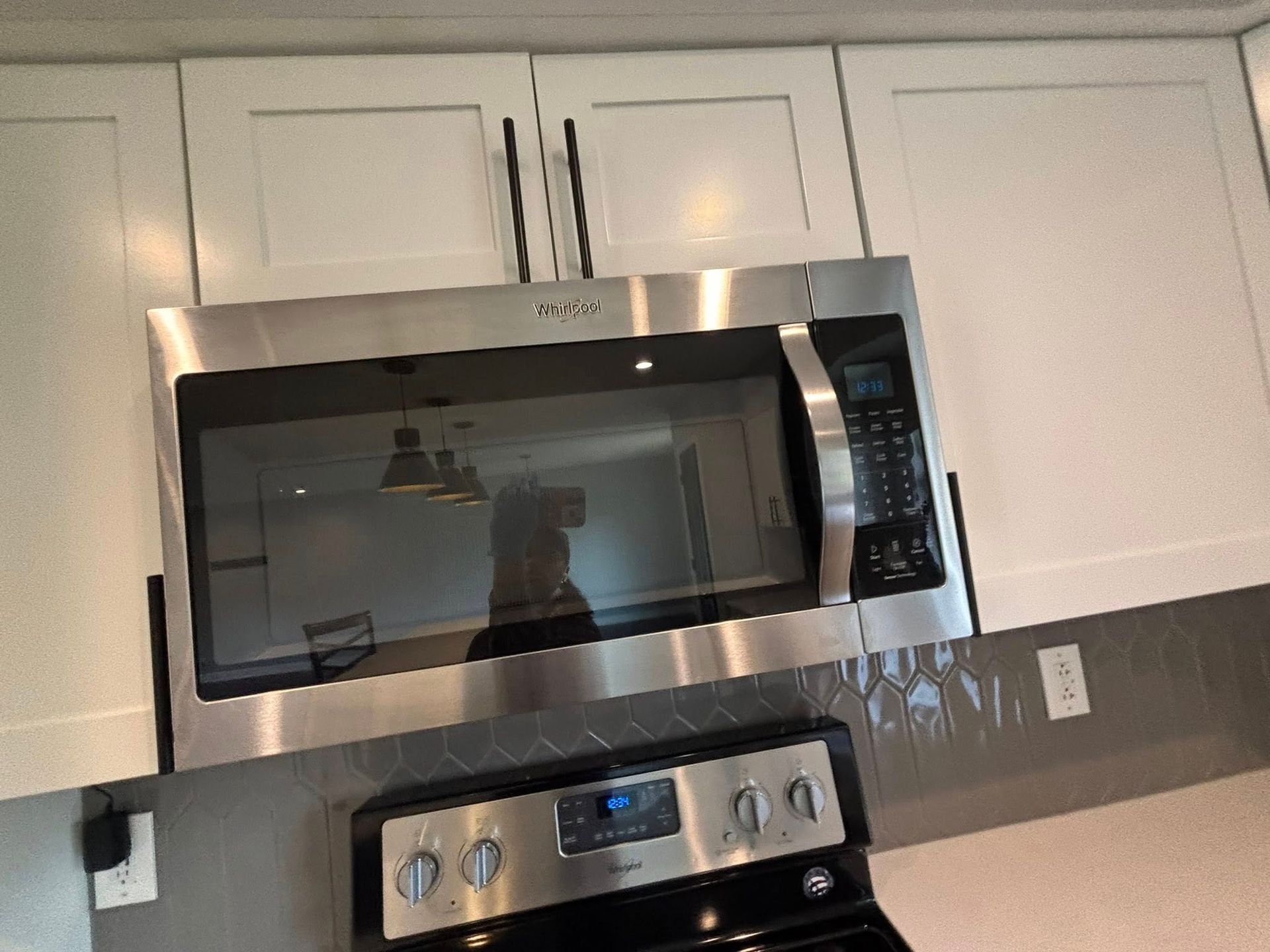 A stainless steel microwave is above a stove in a kitchen