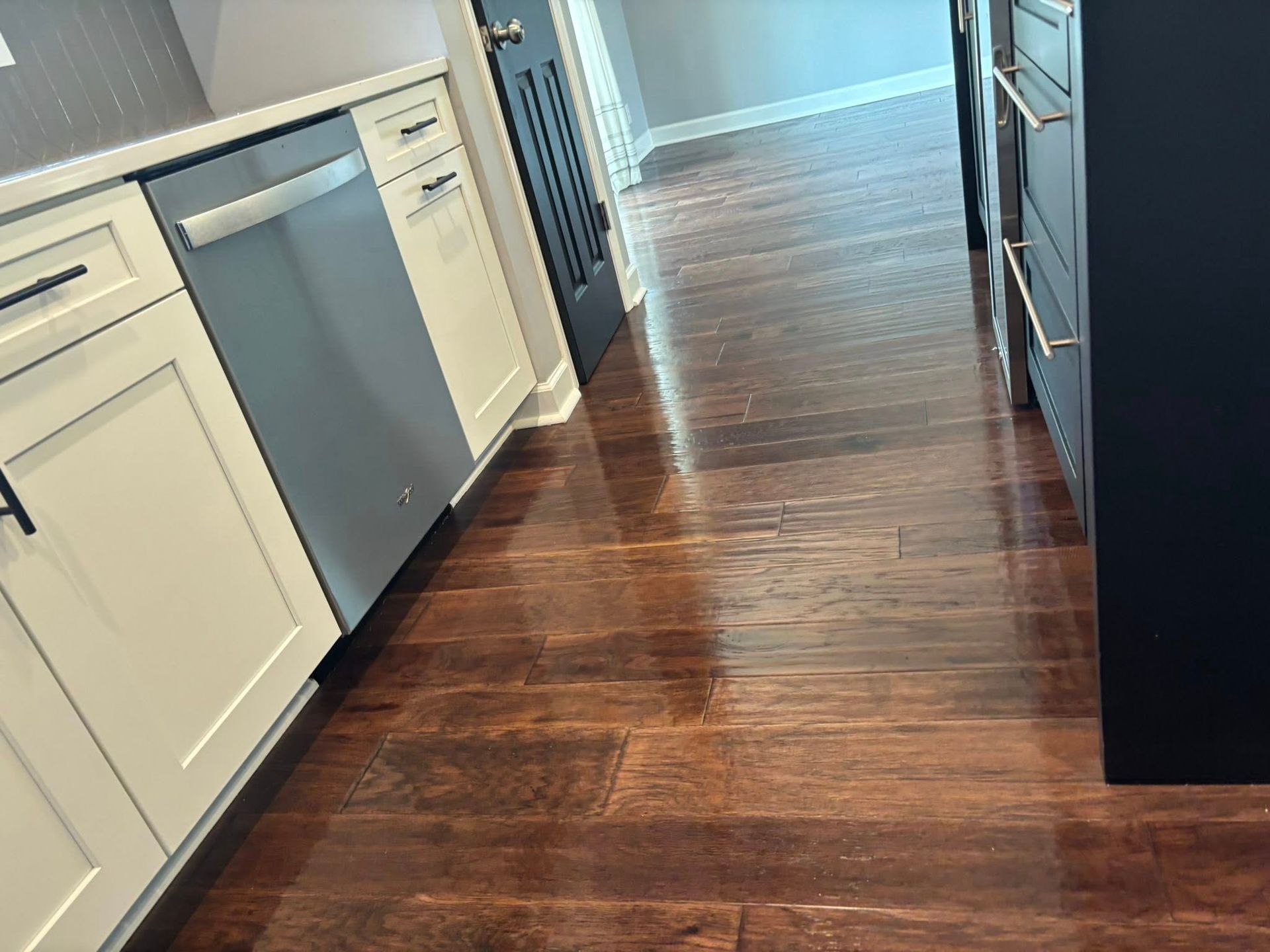 A kitchen with hardwood floors and white cabinets