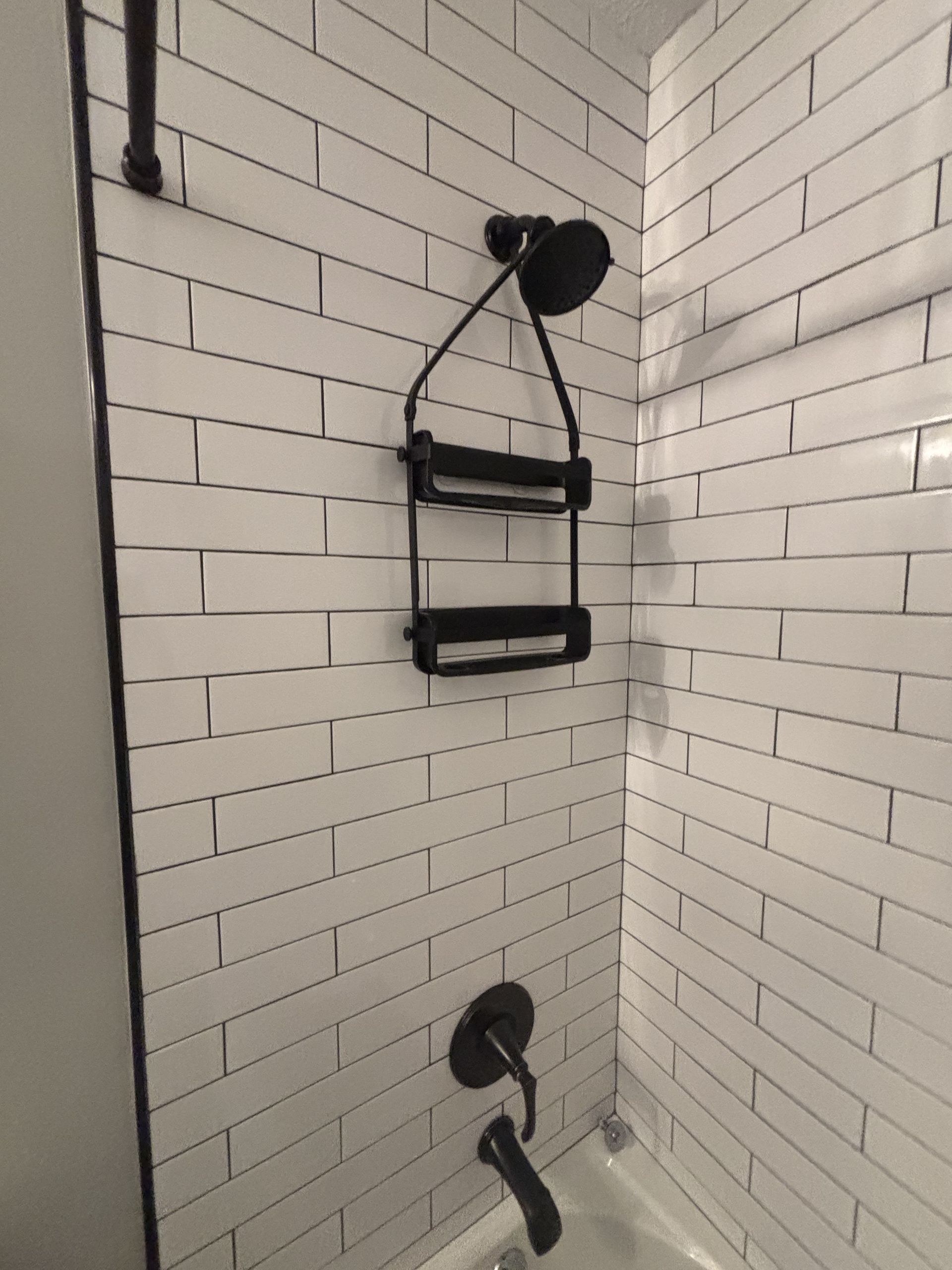 Black shower fixtures against white subway tile.