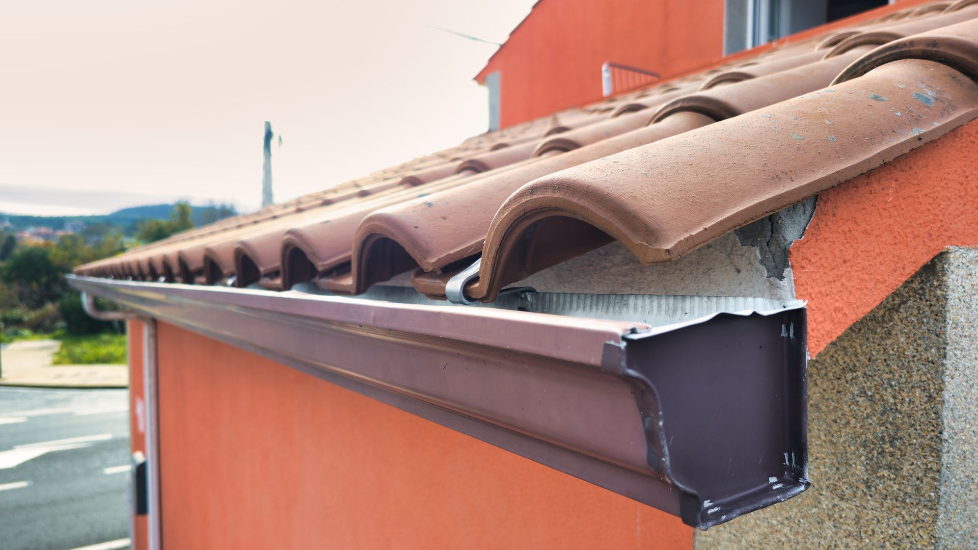A gutter on the side of a building with a tiled roof.