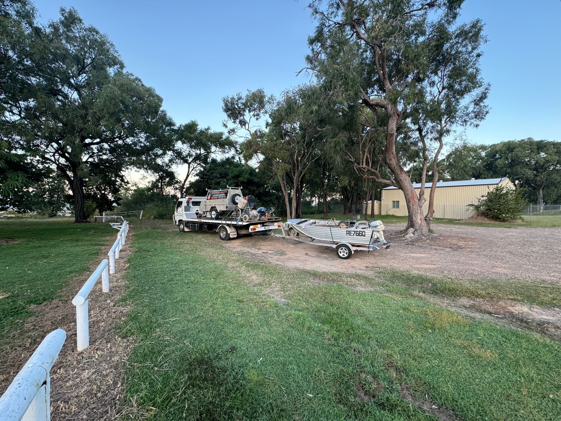 Truck Pulling a Boat on a Trailer Parked on Grass Near Trees and a Building — B&D Auto Group & Towing in Ayr, QLD